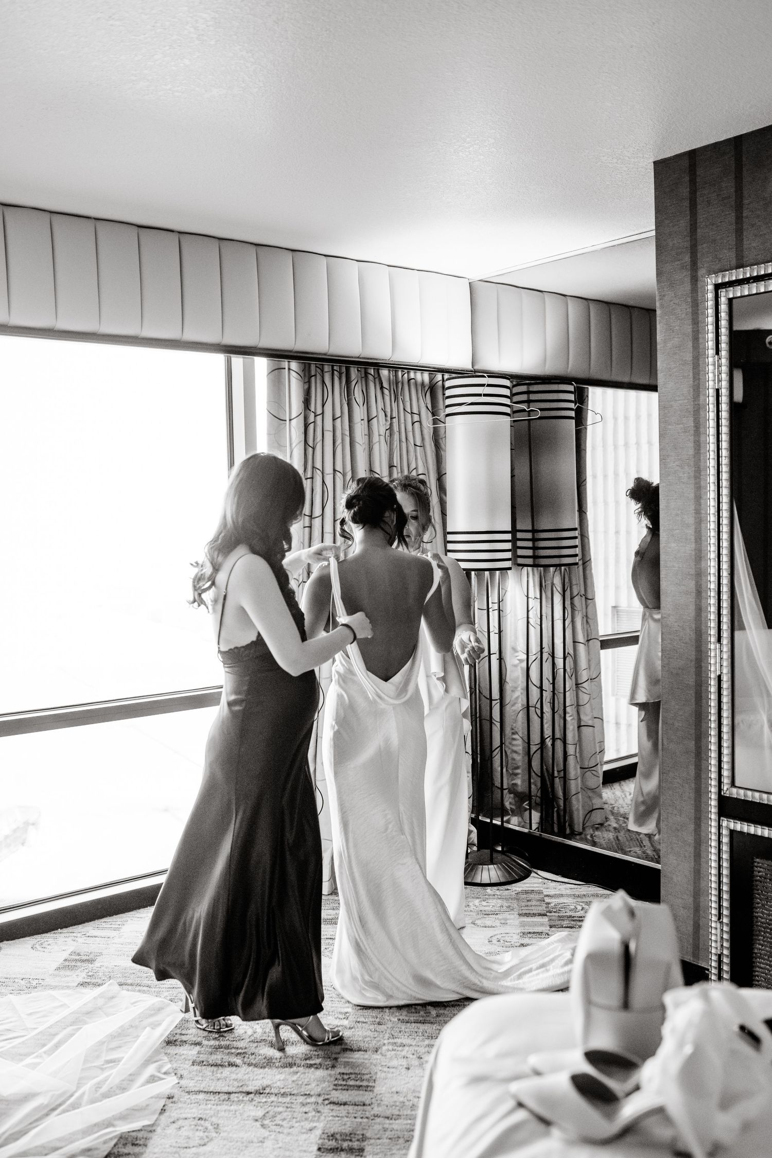 Black and white wedding preparation photos showing a bride getting ready in a hotel room.