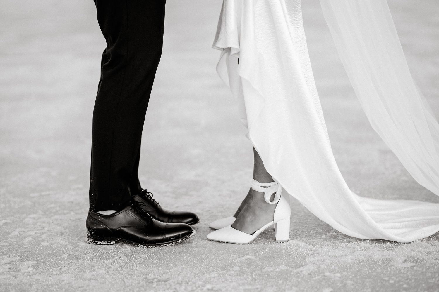Black and white detail shot of bride and groom's feet during wedding ceremony.