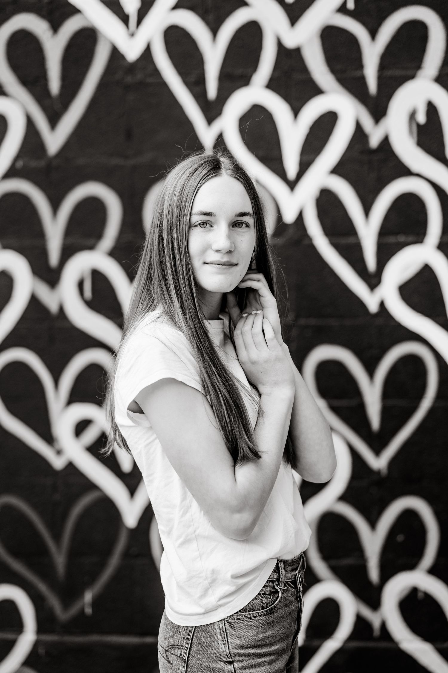 Black and white photo series against a heart pattern wall showing casual poses in jeans and white t-shirt.