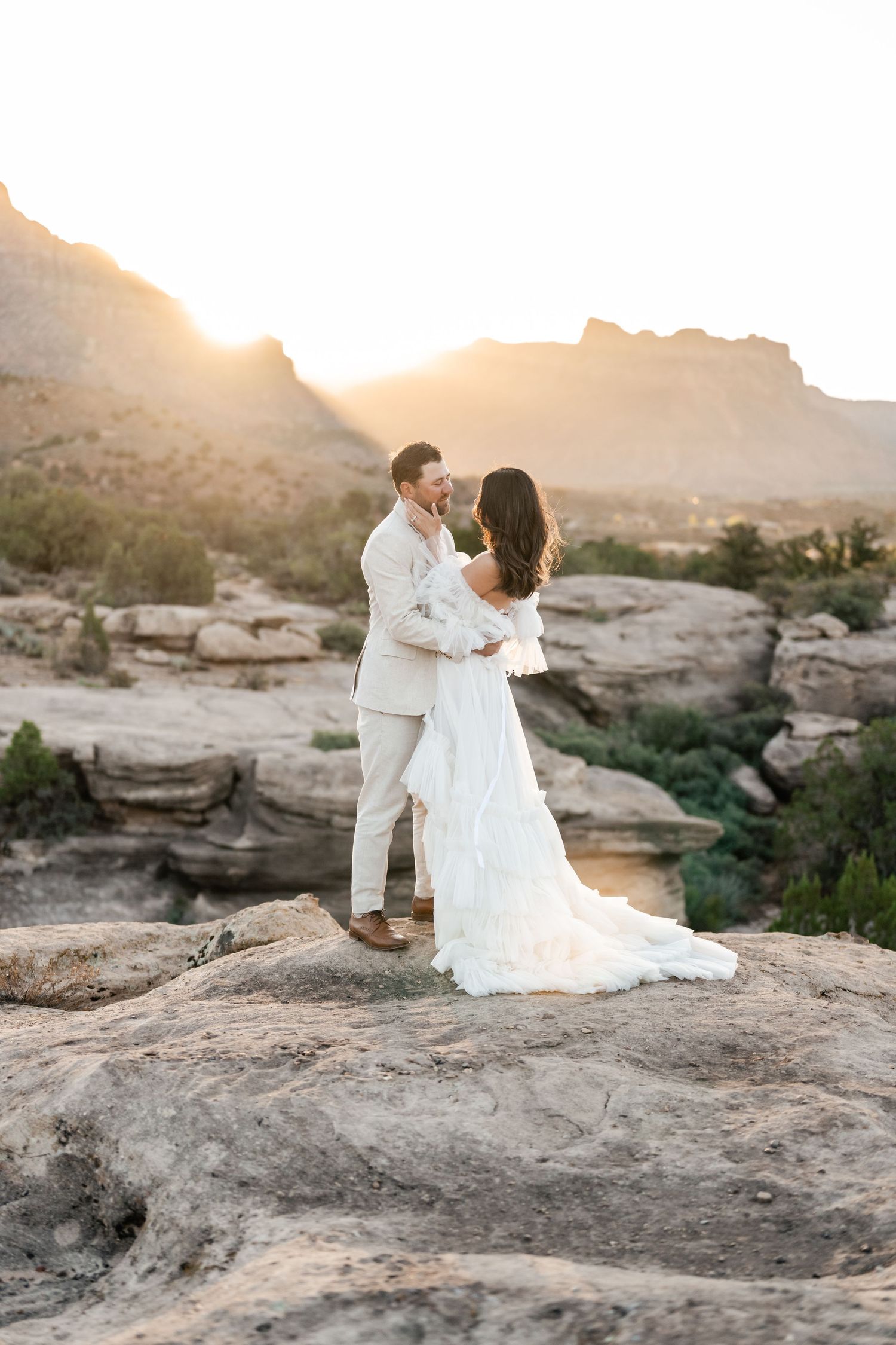 Zion Adventure Session. Romantic desert photoshoot featuring a couple in white formal wear against a mountainous backdrop.