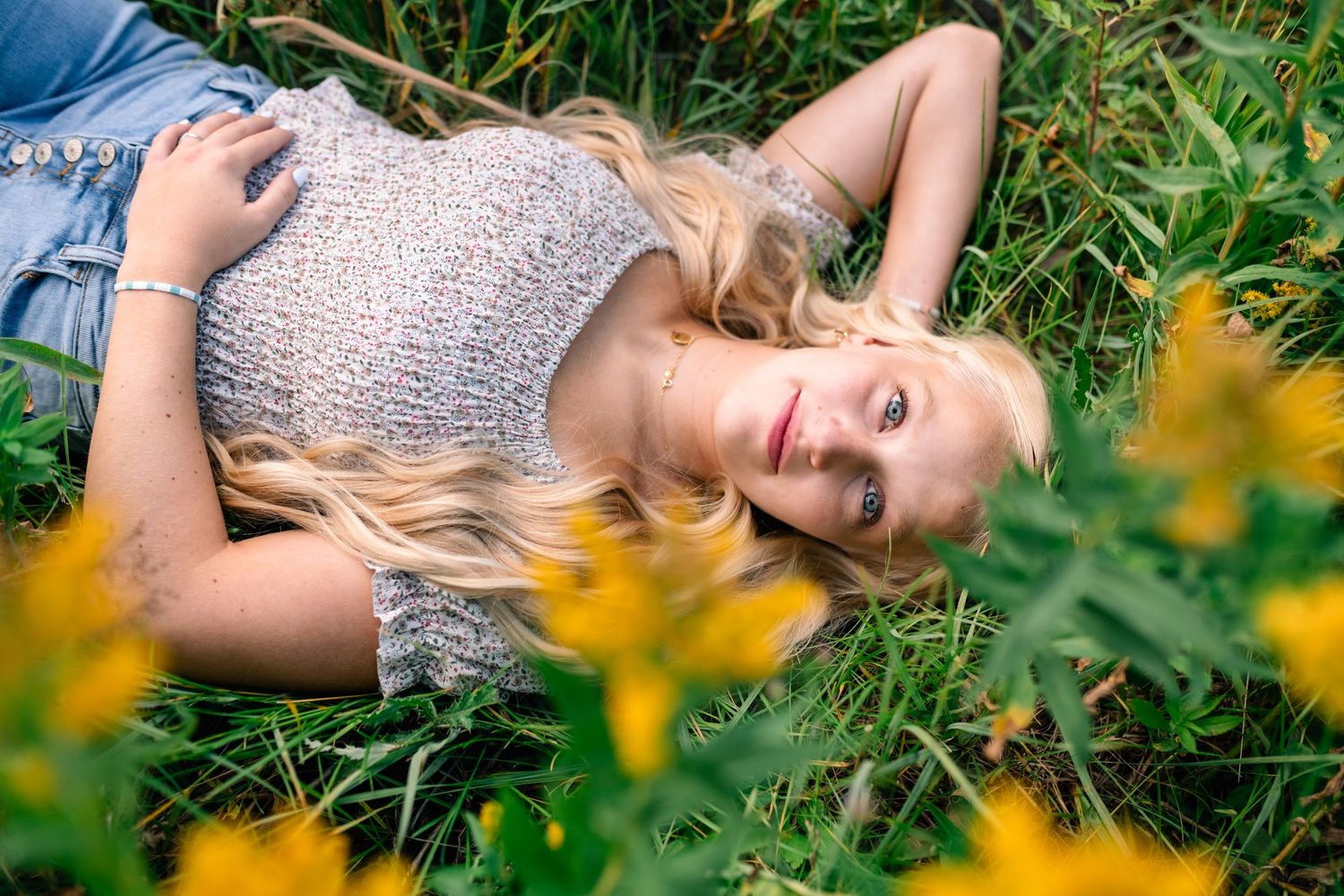 Senior girl lying in a meadow of yellow wildflowers in American Fork Canyon