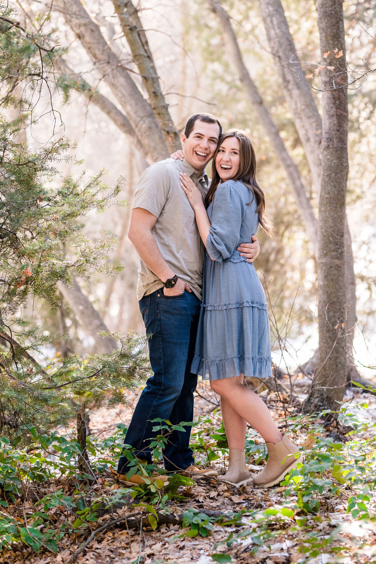 A couple shares a loving moment on a sunlit forest path.