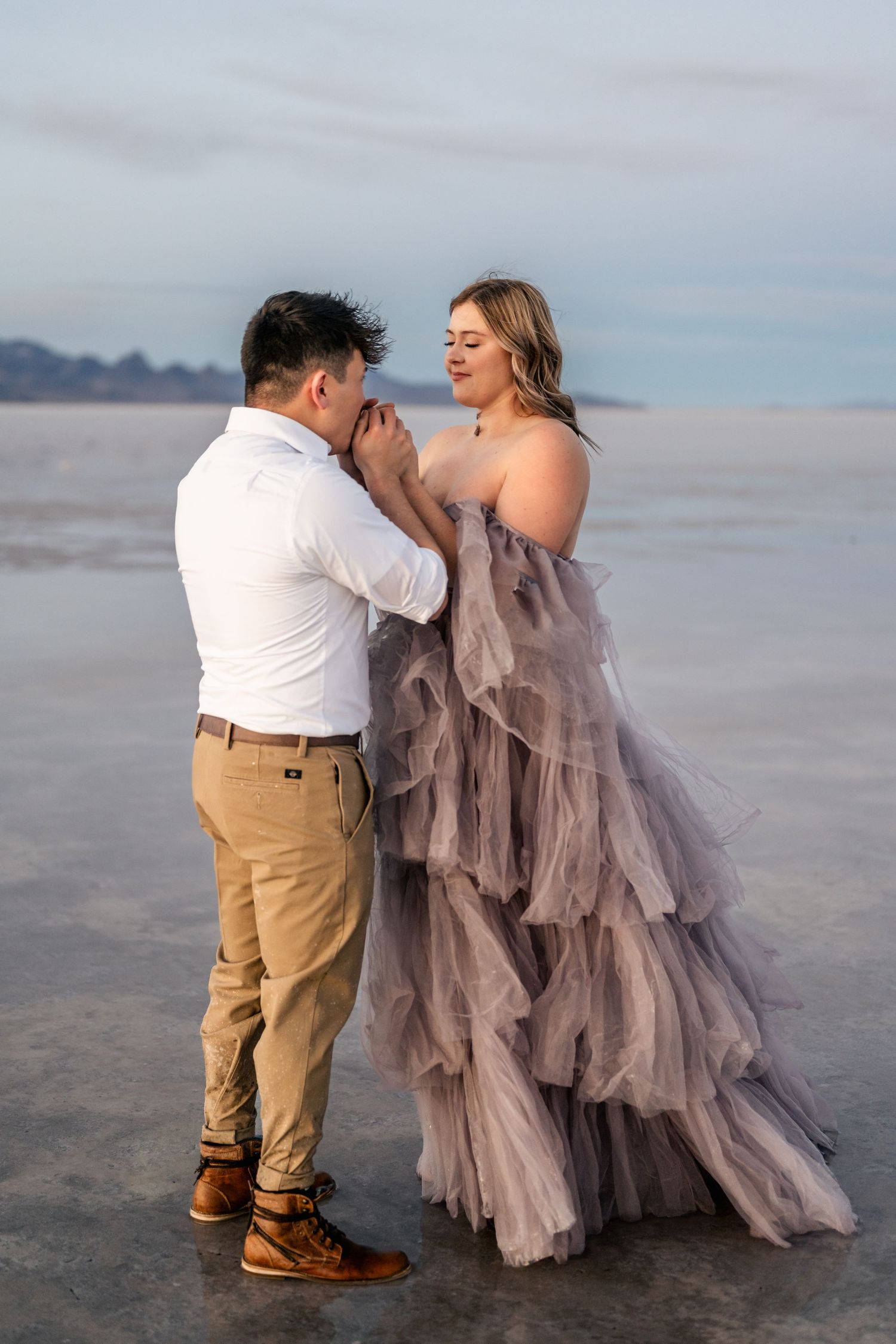 Romantic moment captured as the couple embraces amidst the serene beauty of the flooded Salt Flats during blue hour