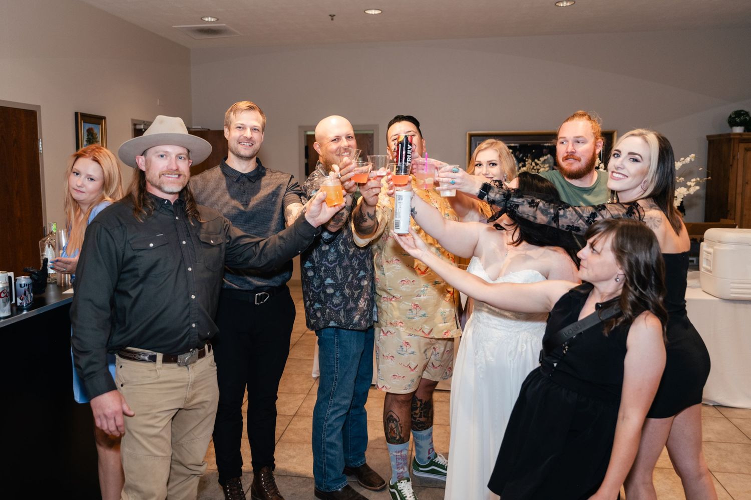 Group of party guests raising glasses together for a celebratory toast at an indoor event.