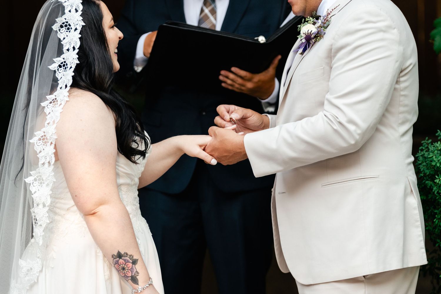 A close-up view of joined hands during an outdoor wedding ceremony.