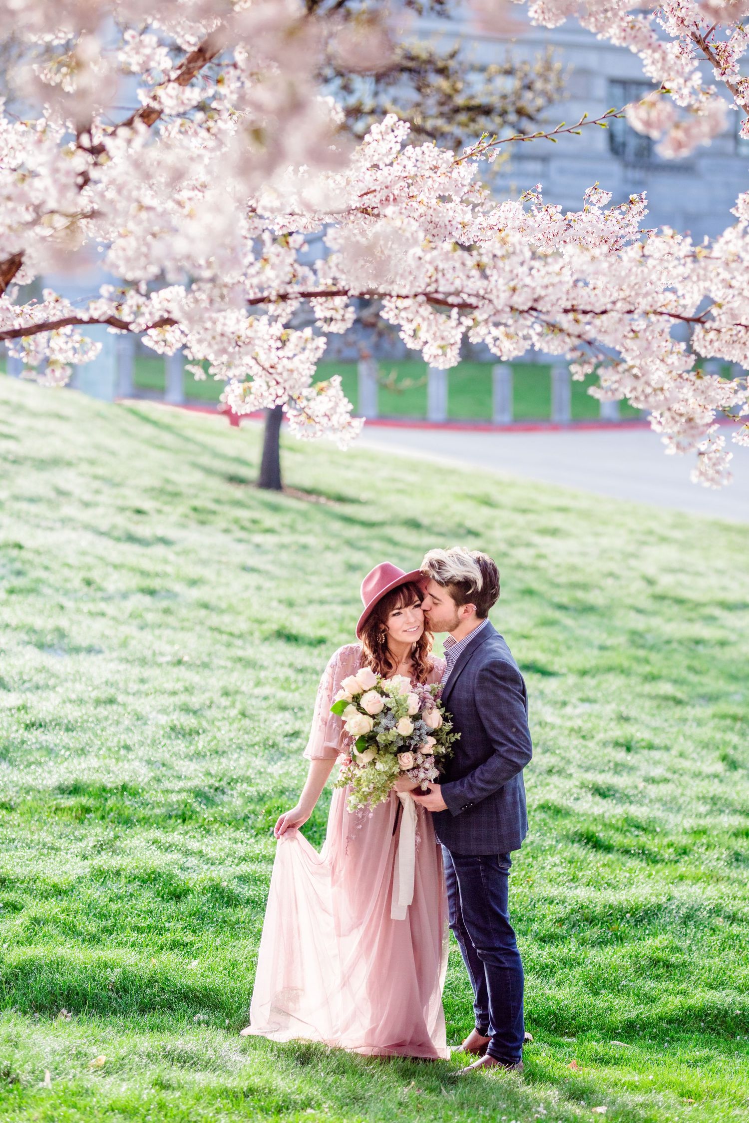 Romantic couple embracing under blooming cherry blossoms in a spring garden setting.