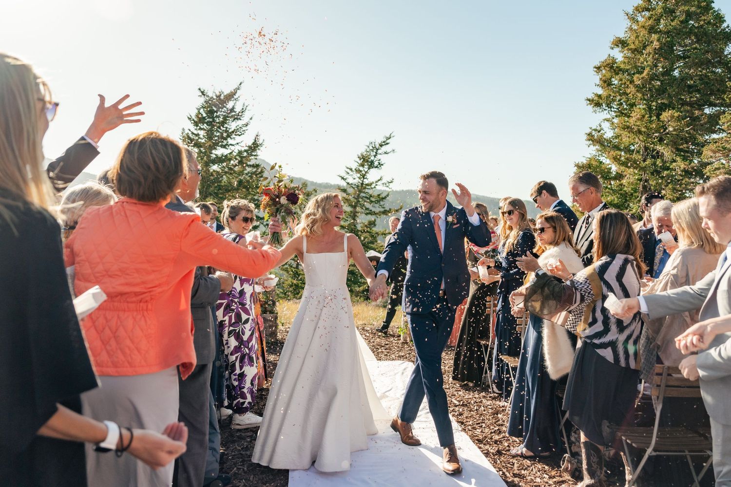 Wedding guests throw flower petals at the newlyweds during an outdoor autumn ceremony. Park City Wedding Photographer. Utah Wedding Photos.