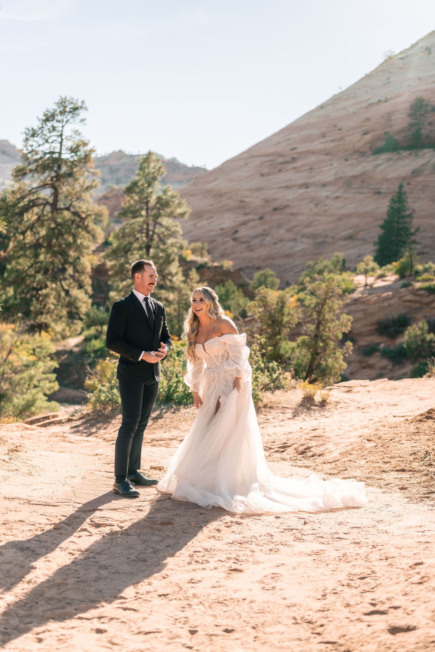 Newlyweds celebrate their wedding day on a scenic desert trail with mountain views.