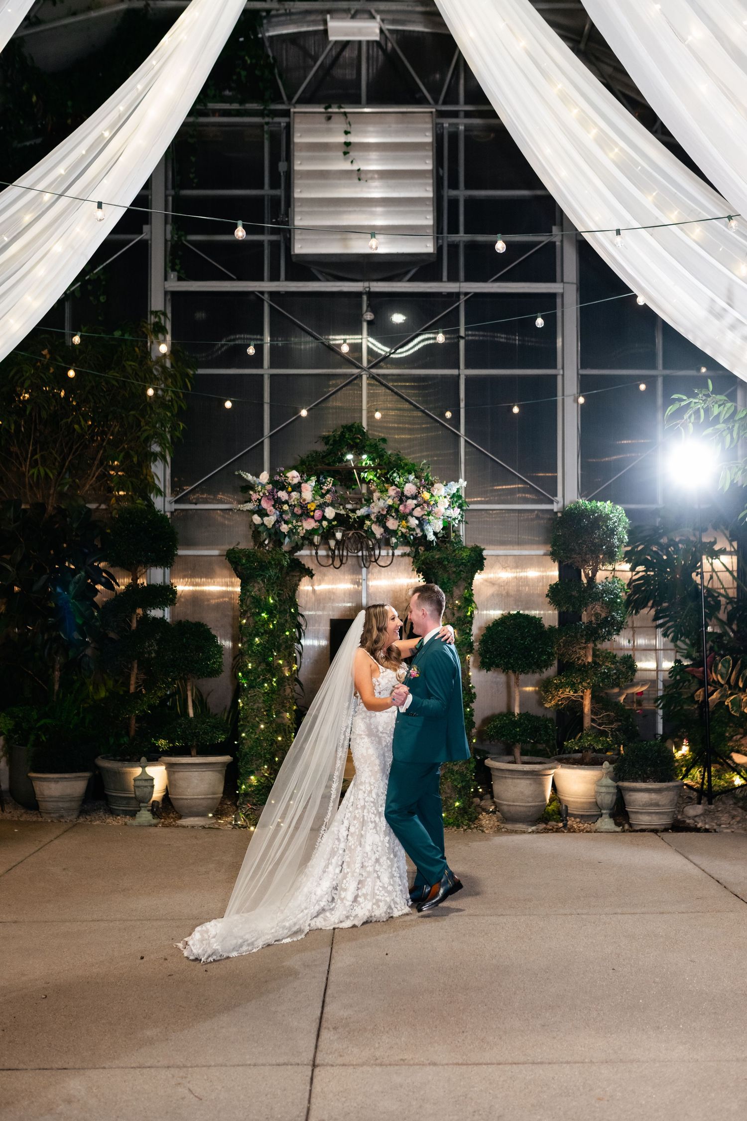 A couple shares their first dance at an elegant greenhouse wedding venue with ambient lighting. Cactus & Tropicals Photographer.