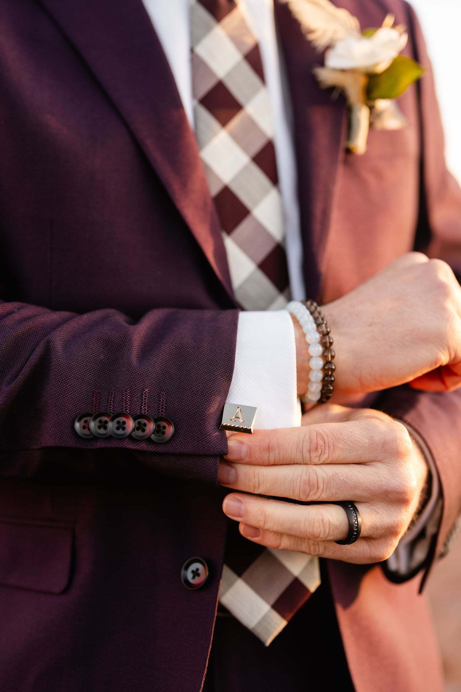 Close-up detail of formal attire with a burgundy suit jacket and checkered tie.