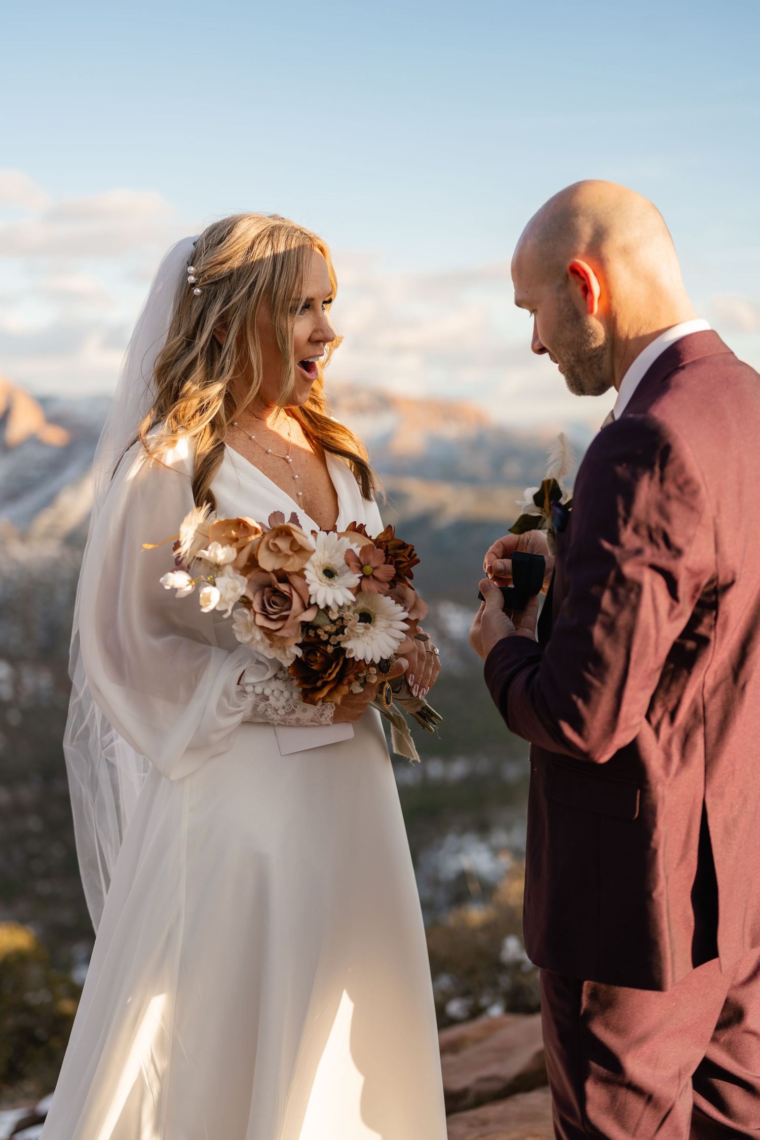 A wedding couple shares a joyful moment during their mountain ceremony with dramatic landscapes behind them.