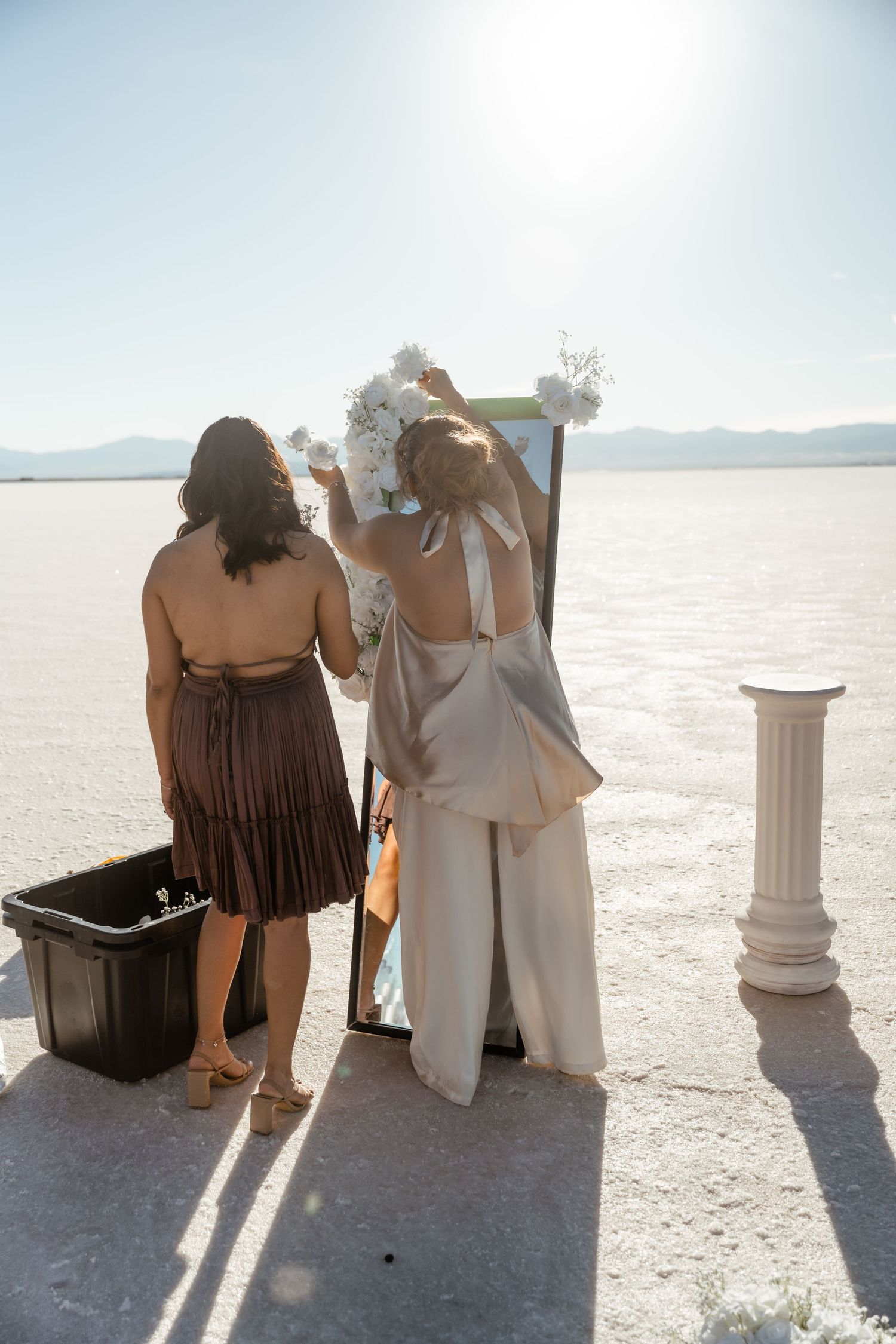 Two people sit together on chairs against a stark white salt flat landscape.