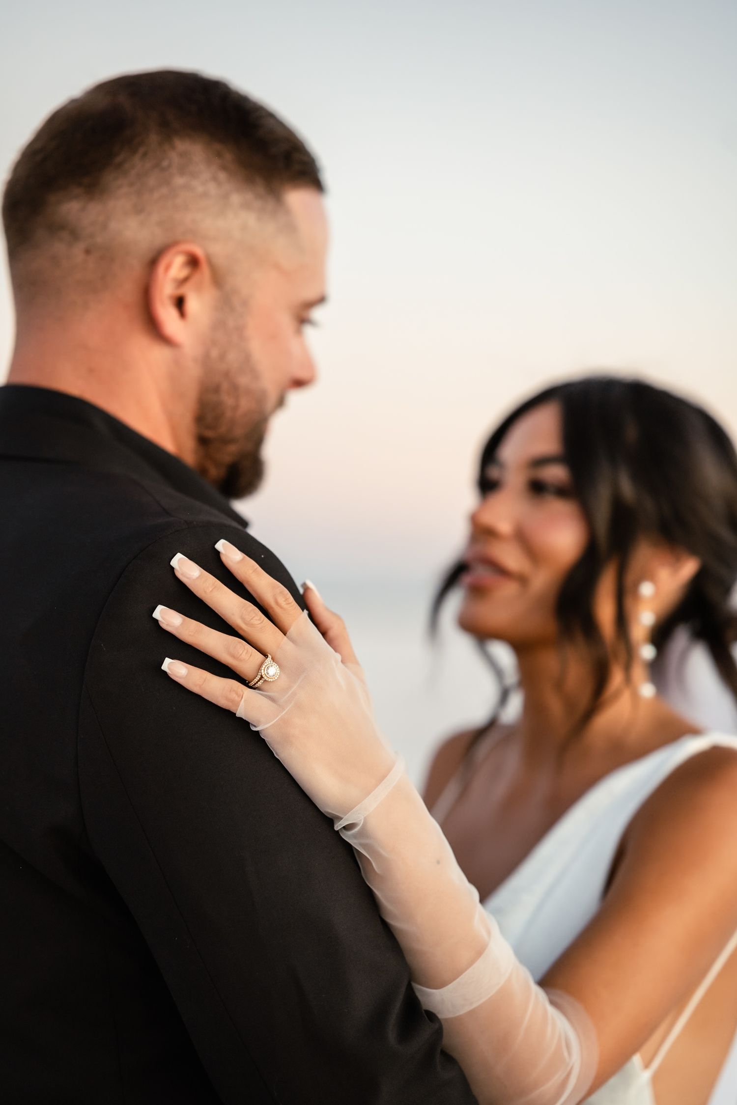 Close-up of couple embracing during sunset wedding ceremony.
