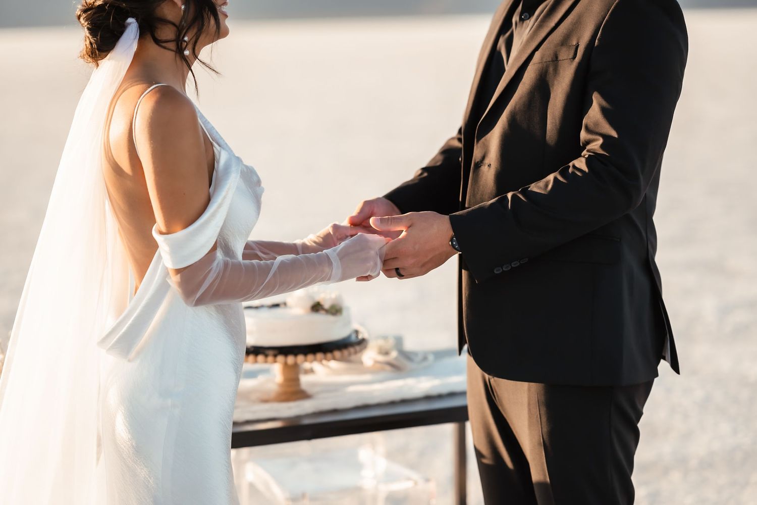 A couple exchanges rings during their wedding ceremony on a bright salt flat.