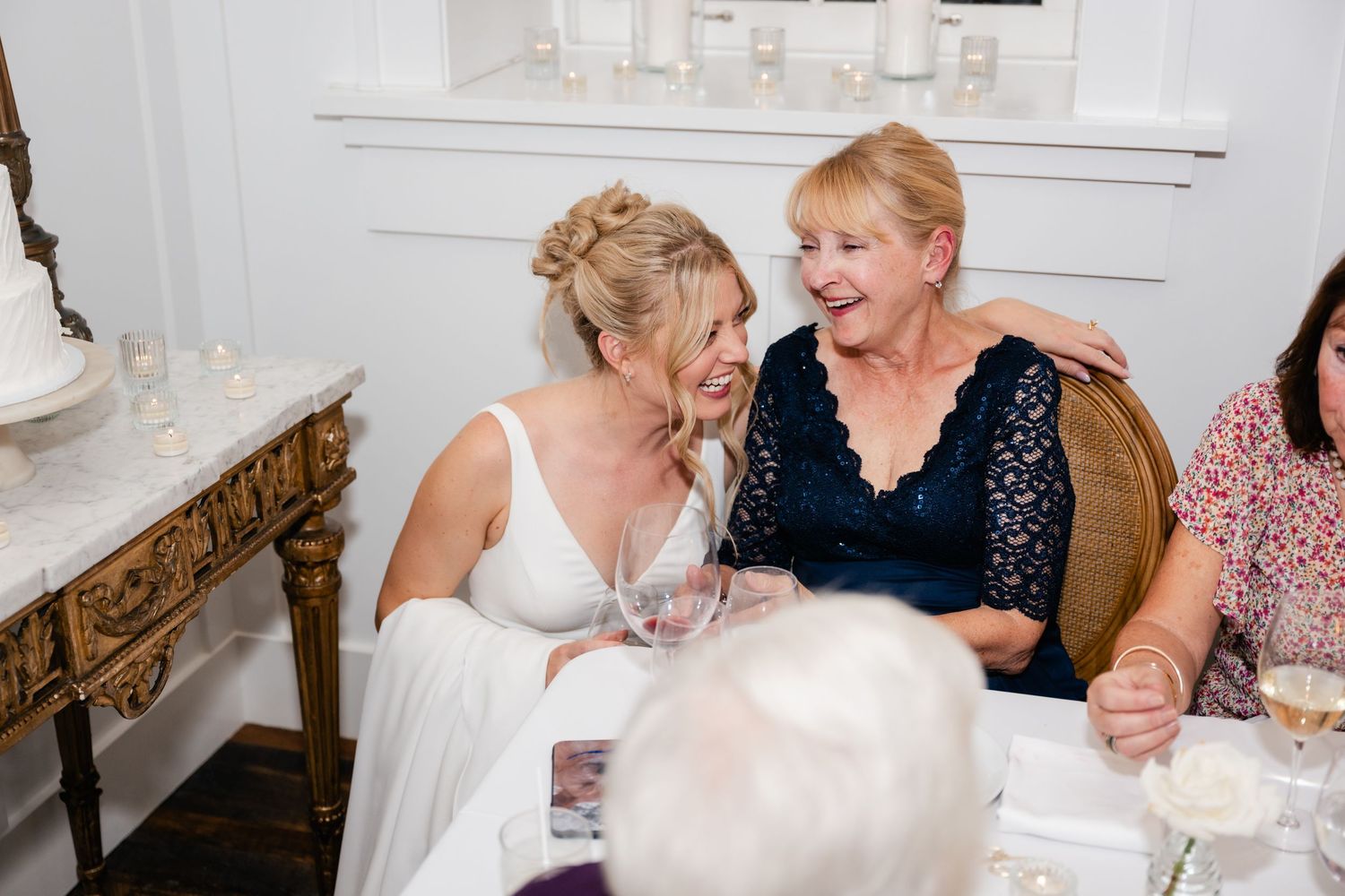 Two people in formal attire share a joyful moment while seated at an elegant table during a special occasion.