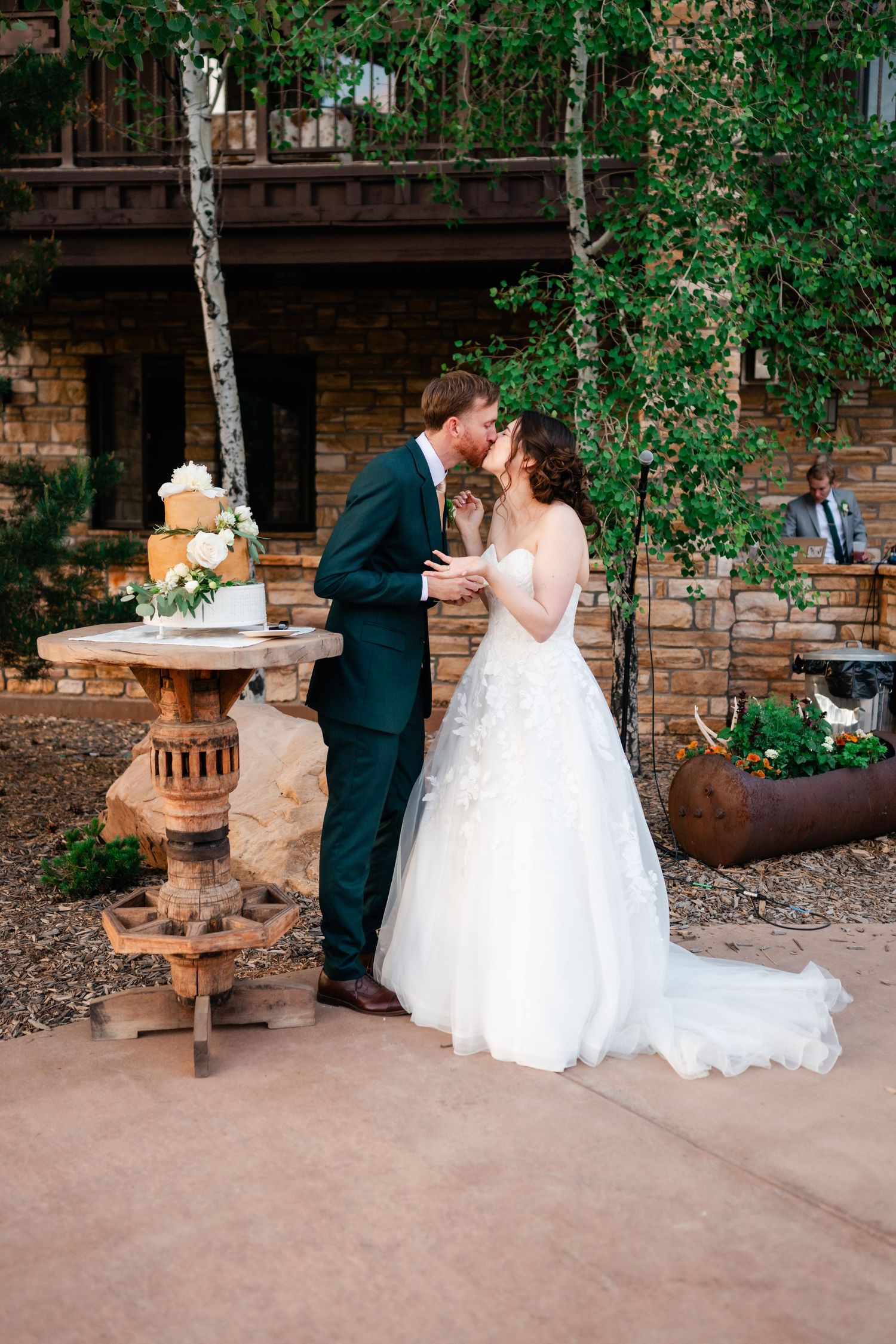 A romantic wedding couple shares a kiss during their cake cutting at their ranch venue by Utah Wedding Photographer Coley Cook.