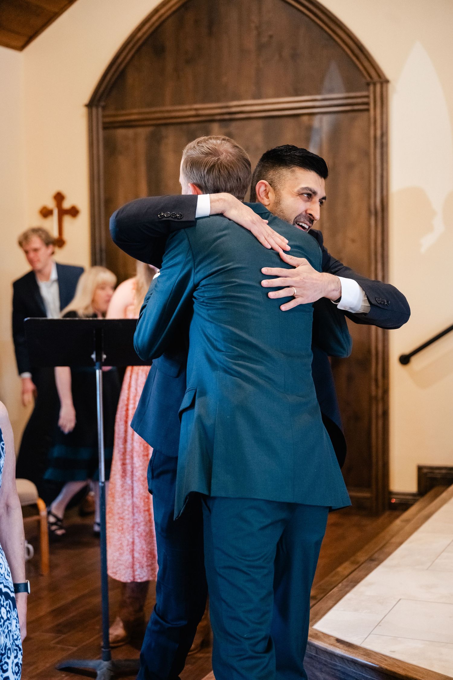 Series of warm hugs exchanged between people in formal wear at a wedding.