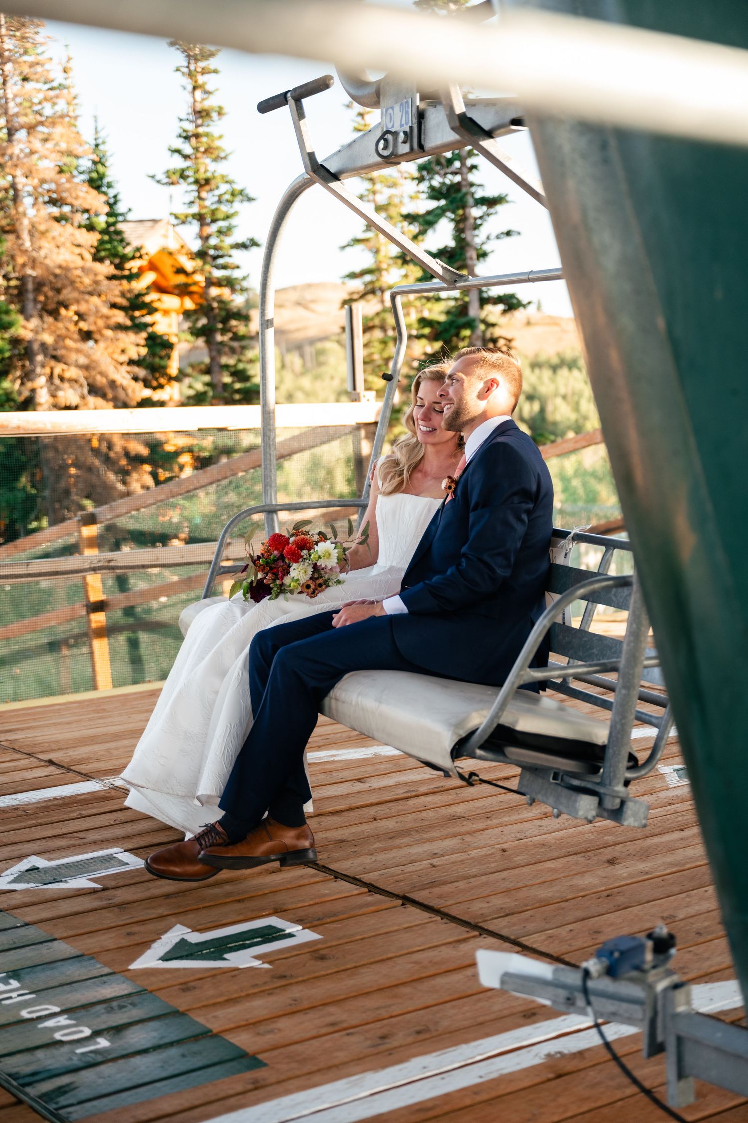 Couple rides chairlift together at mountain resort during sunset wedding celebration.