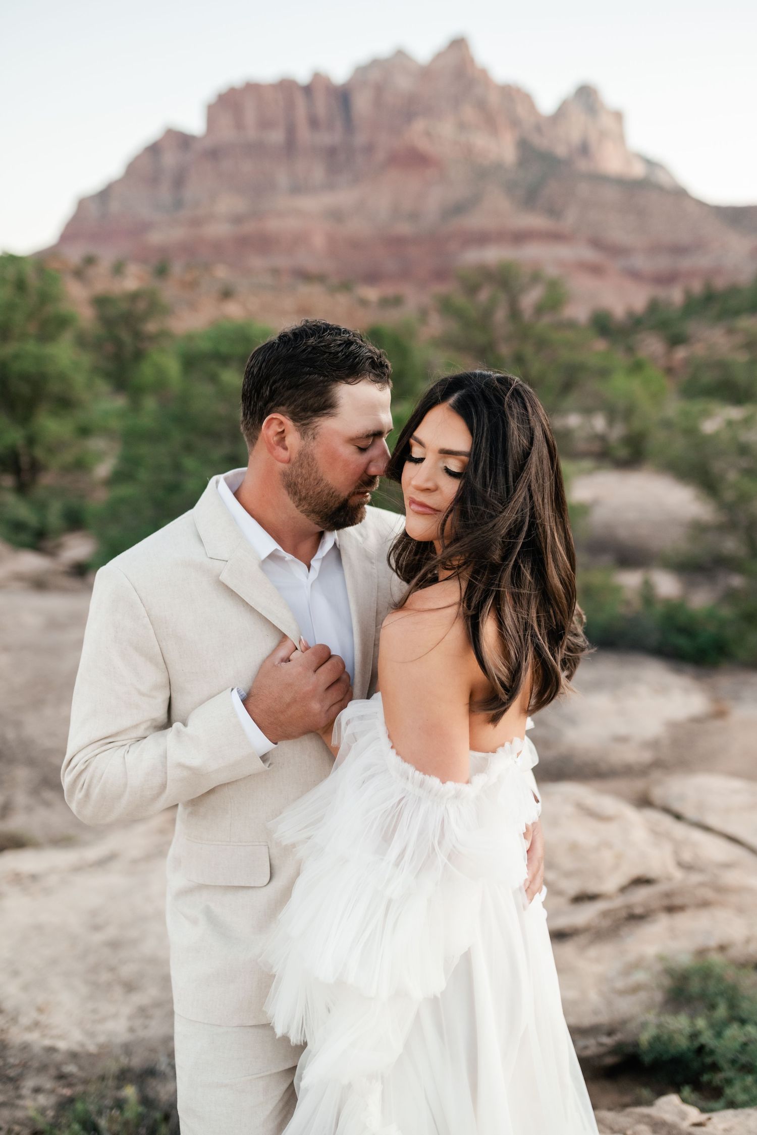 Zion Adventure Session. Intimate wedding portraits taken on rocky terrain with majestic desert mountains behind.