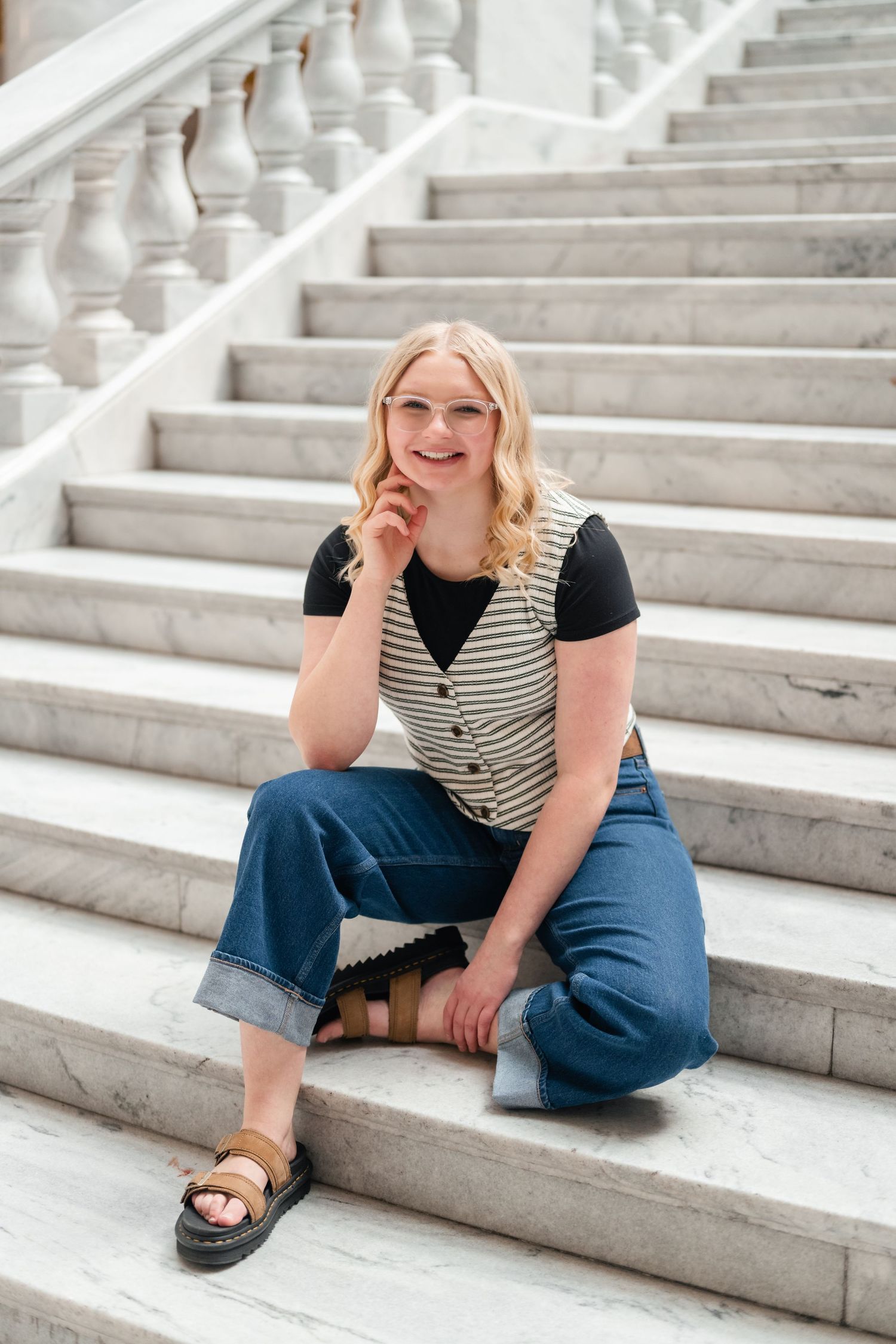 A casual portrait series on white marble steps showing relaxed poses in jeans and striped vest.