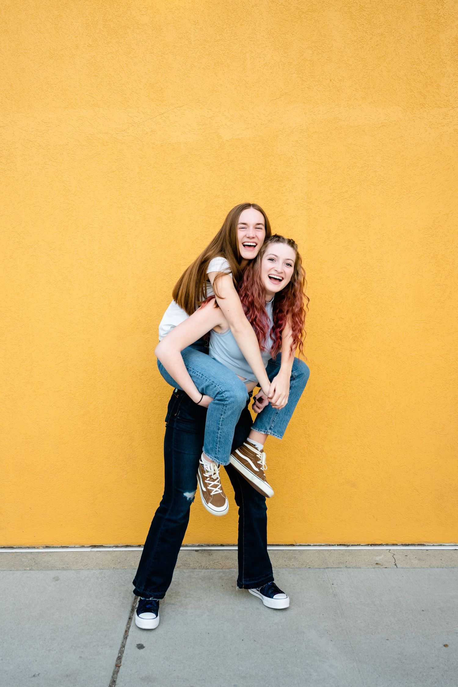 Person in casual wear laughs while bending forward against a bright yellow wall in a playful sequence.