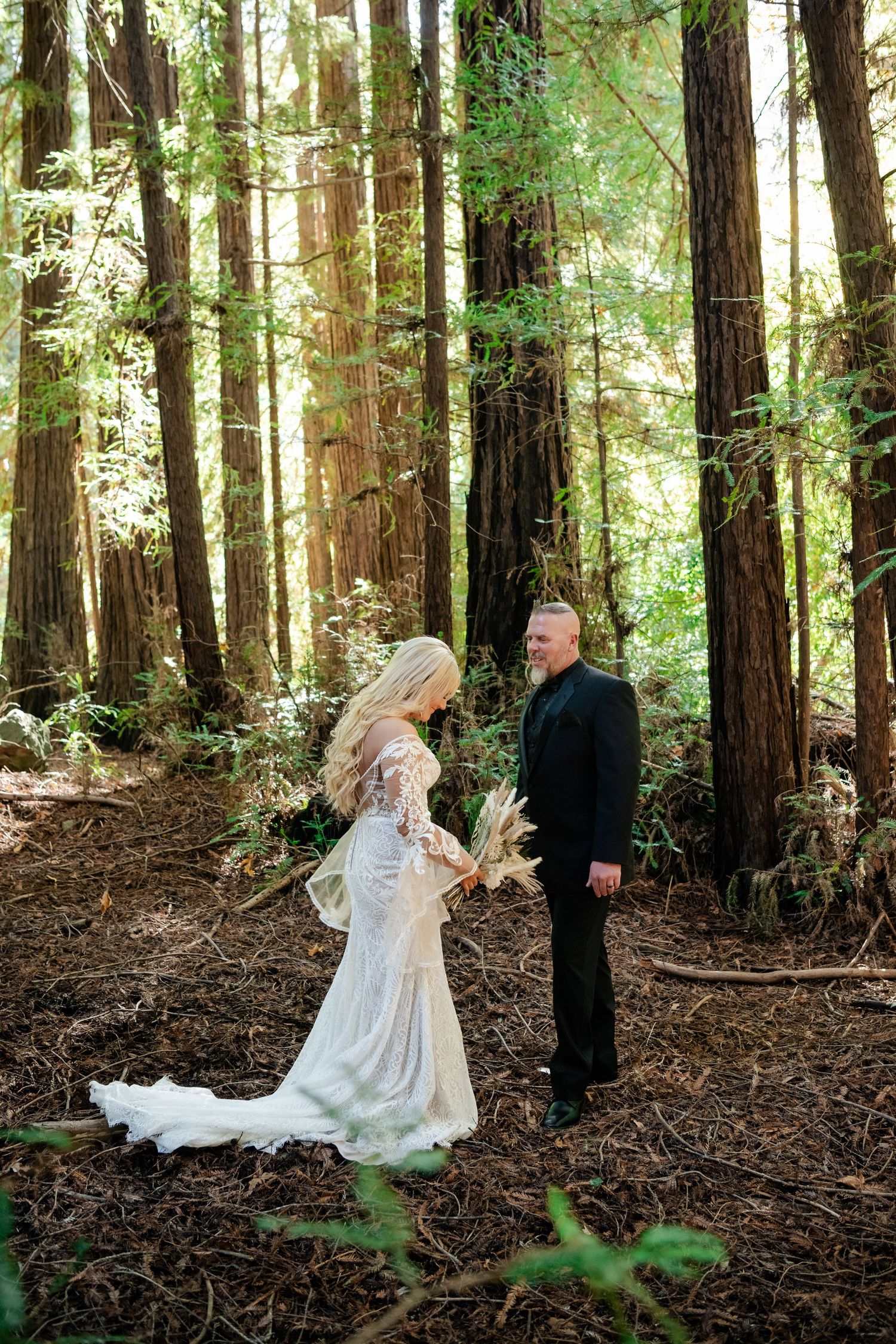 A romantic wedding photoshoot in a serene redwood forest with sunlight filtering through tall trees.
