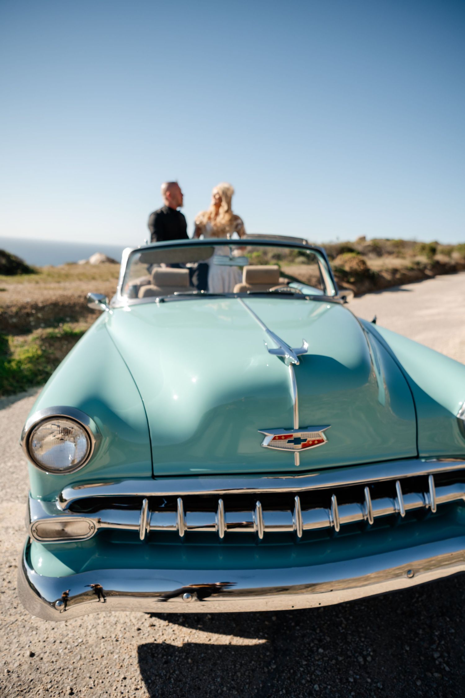Classic turquoise Chevrolet convertible photographed in segments against coastal backdrop.