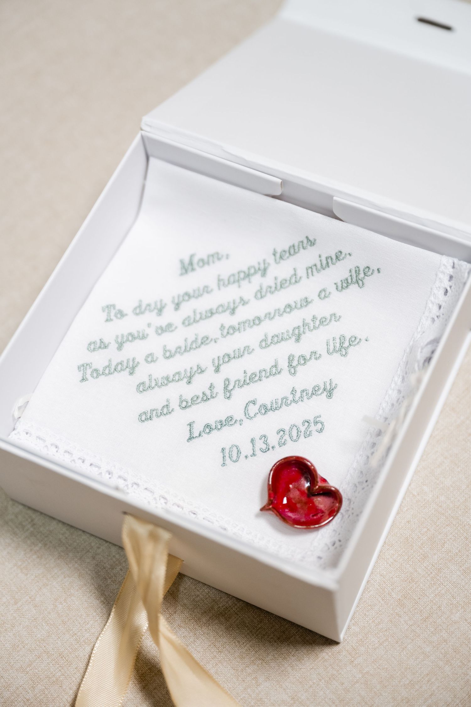 White wedding invitation boxes with handwritten text and red wax seals tied with gold ribbon.