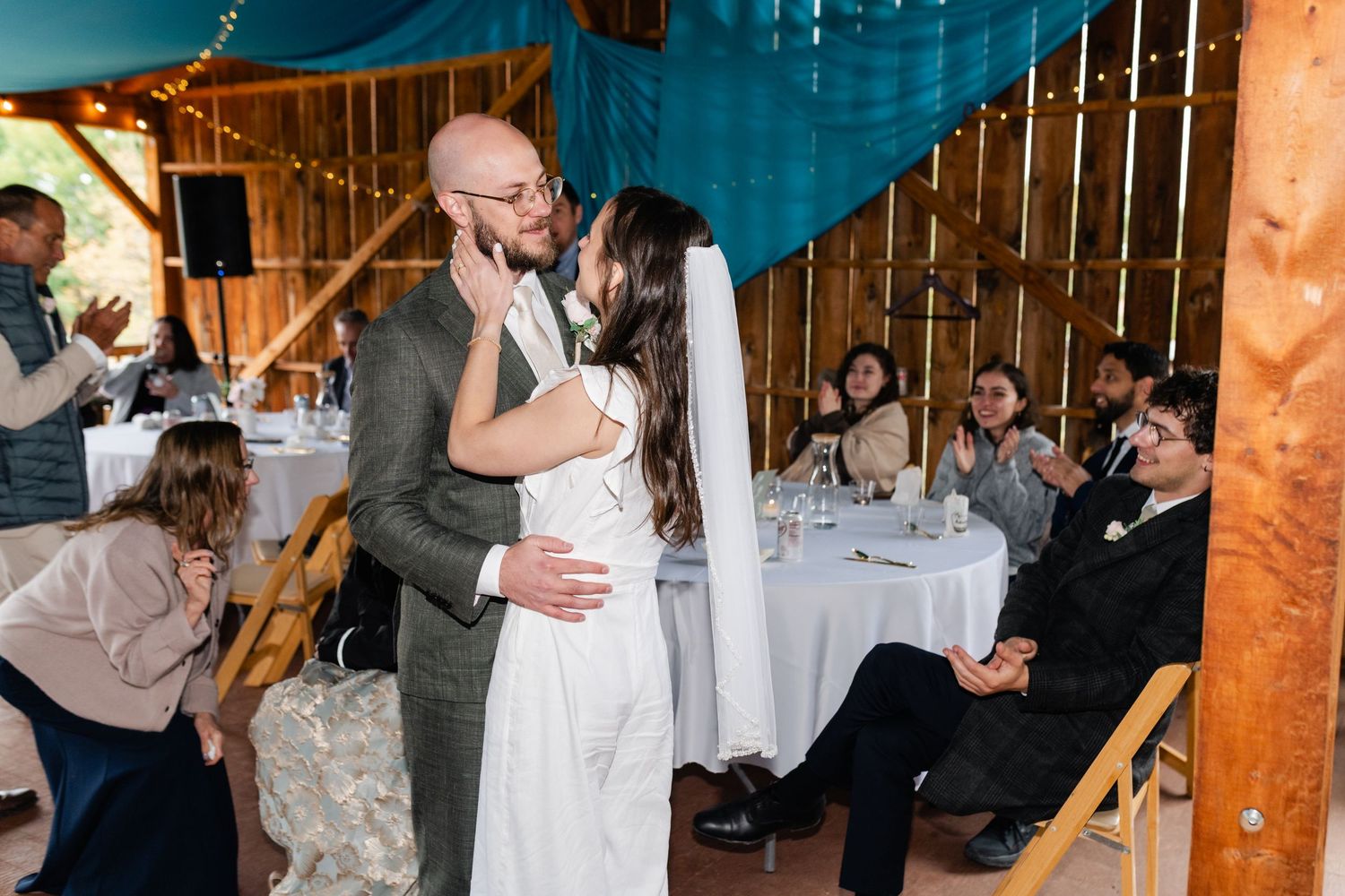 Newlyweds sharing an intimate moment during their reception as guests look on.