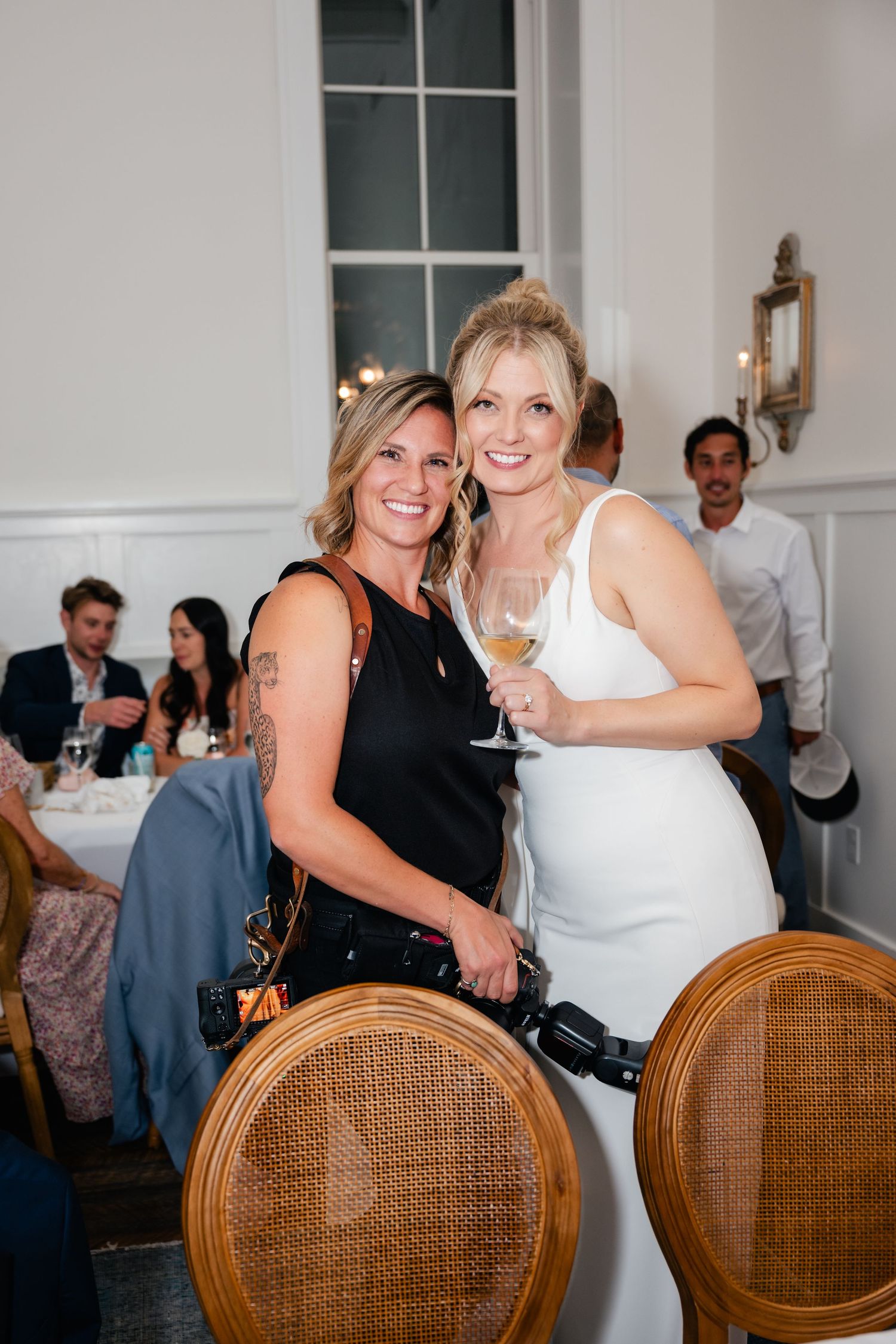 Wedding guests seated at wooden cane-back chairs share joyful moments during the reception.