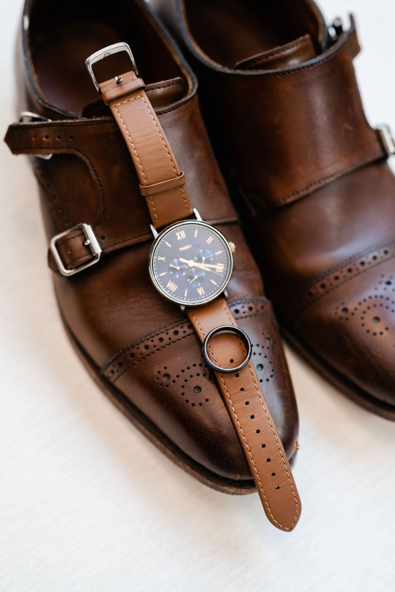 Brown leather dress shoes with watch and wedding rings arranged for detail photography. Park City Wedding Photographer.