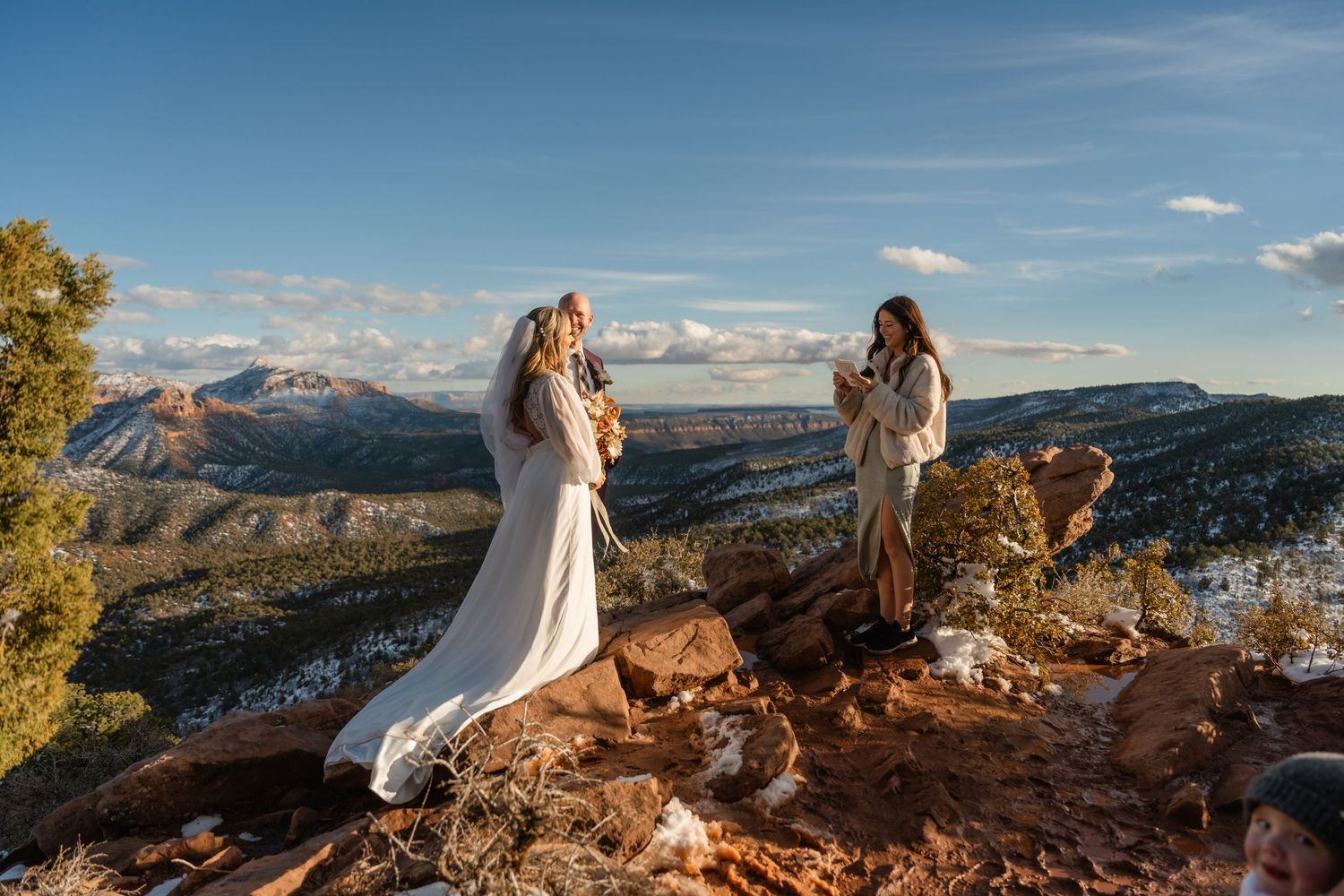 Wedding ceremony on mountain overlook with vast desert landscape.