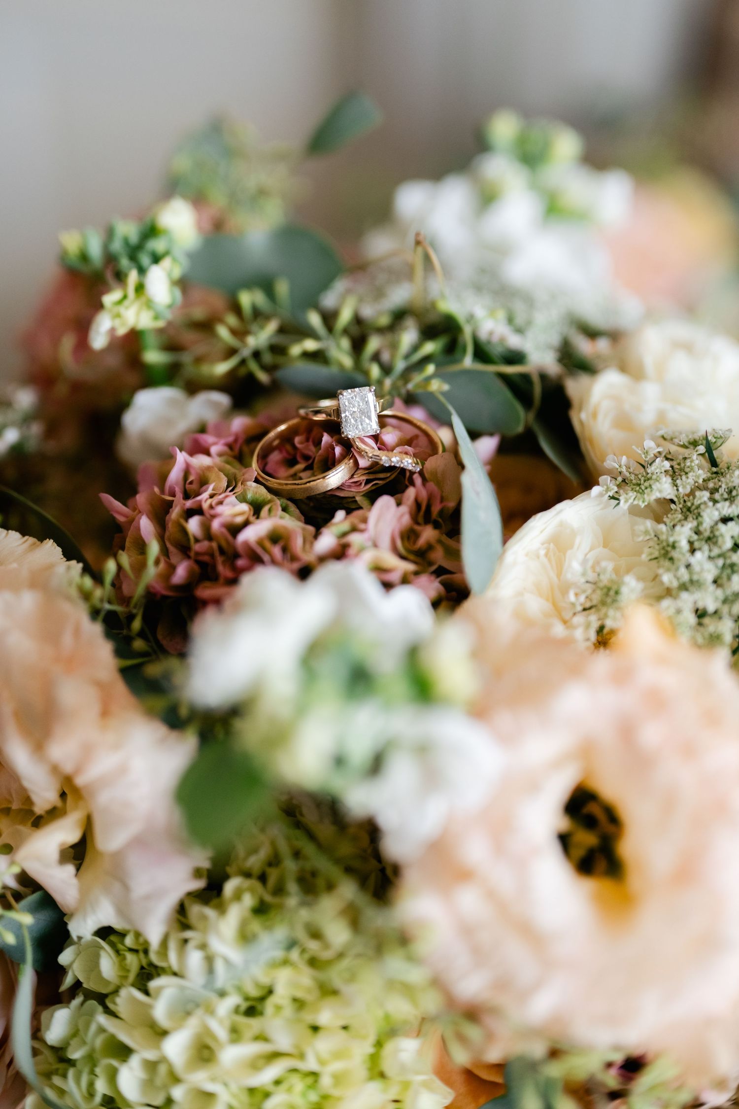 Delicate floral arrangement featuring soft pink and burgundy blooms with green foliage in a dreamy macro shot.