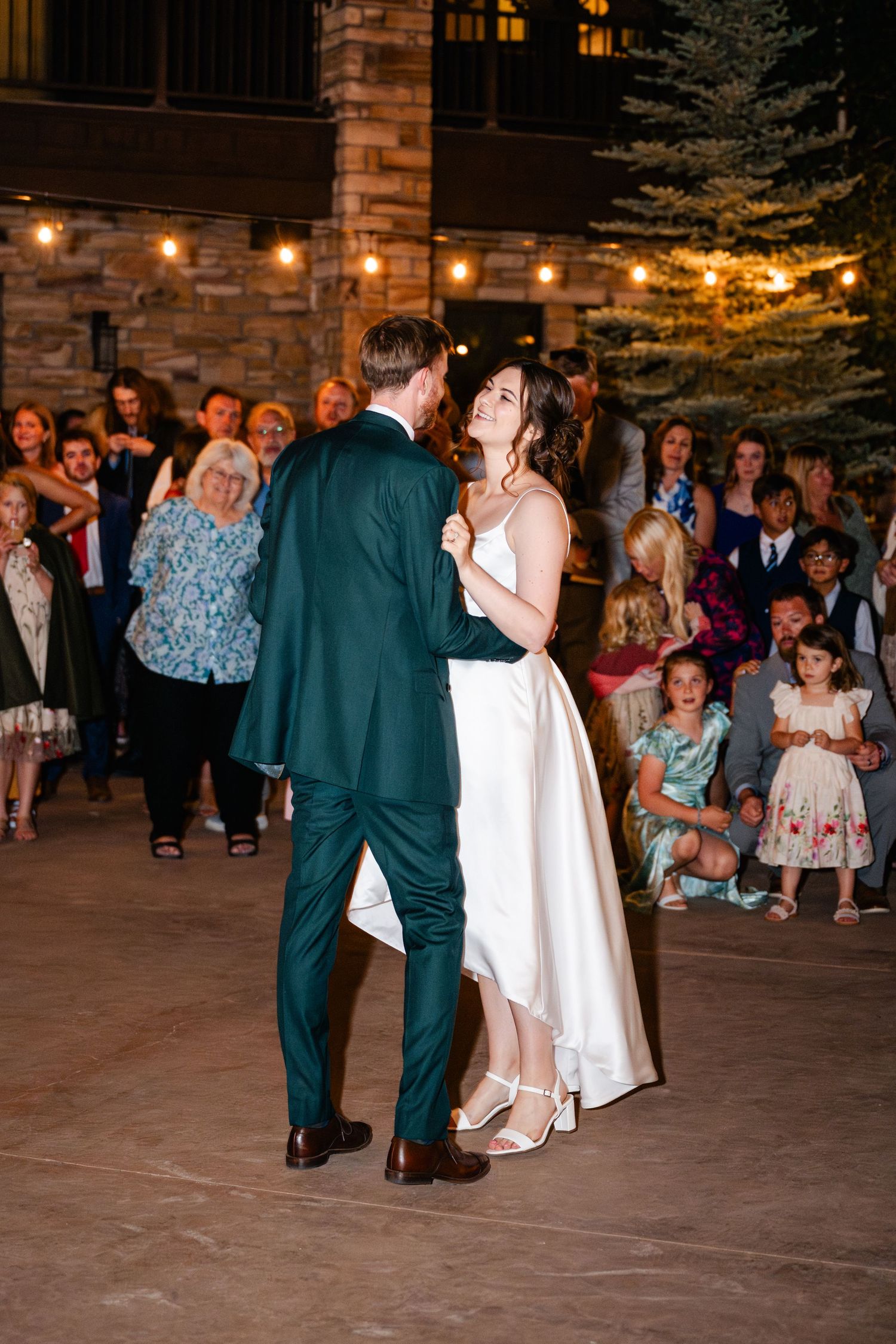 Wedding reception dance floor with string lights overhead and couples dancing in formal attire.
