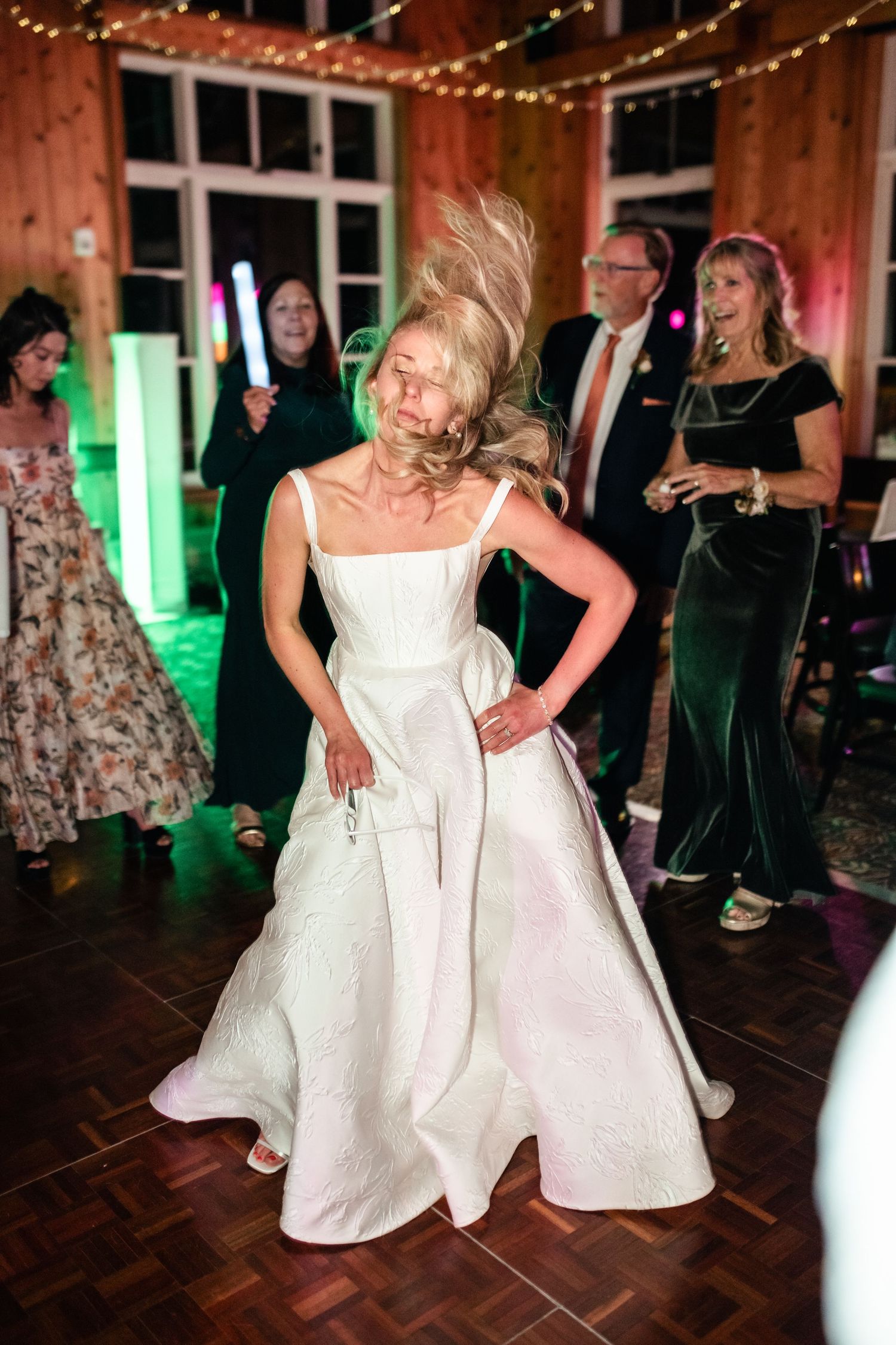 Bride in white gown twirls on dance floor during wedding reception.