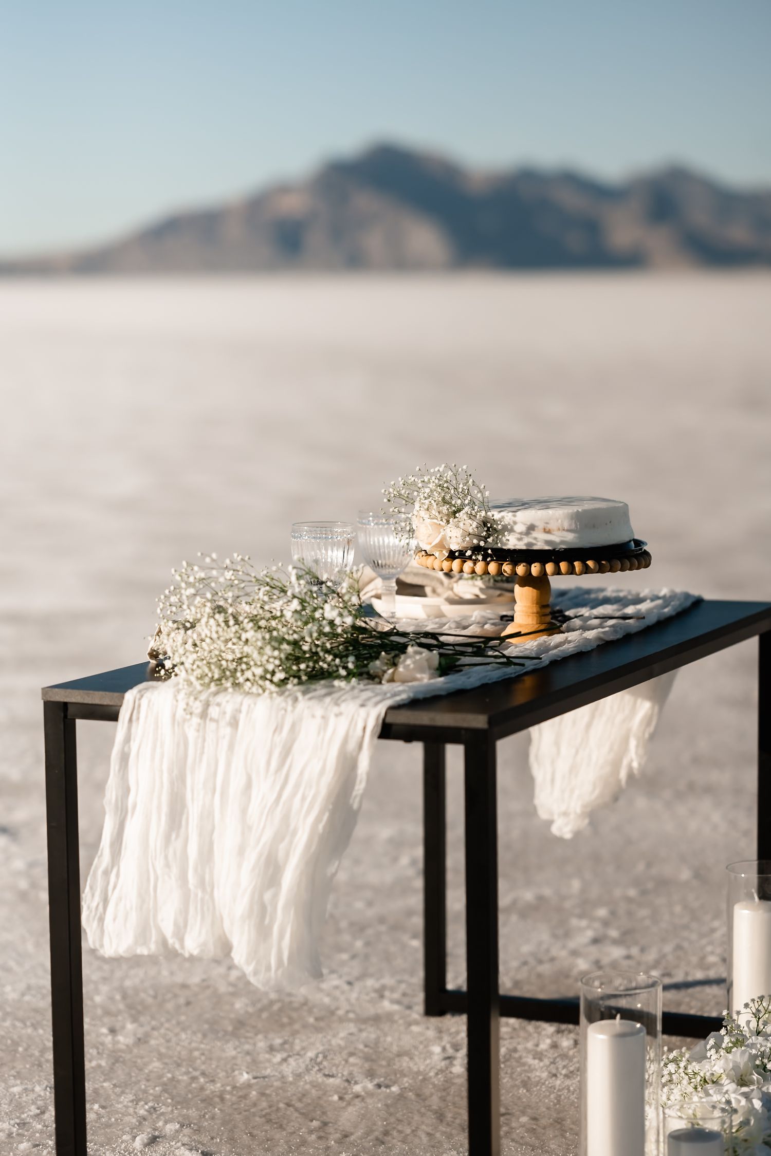 Minimalist black reception tables decorated with white linens and baby's breath on salt flats.