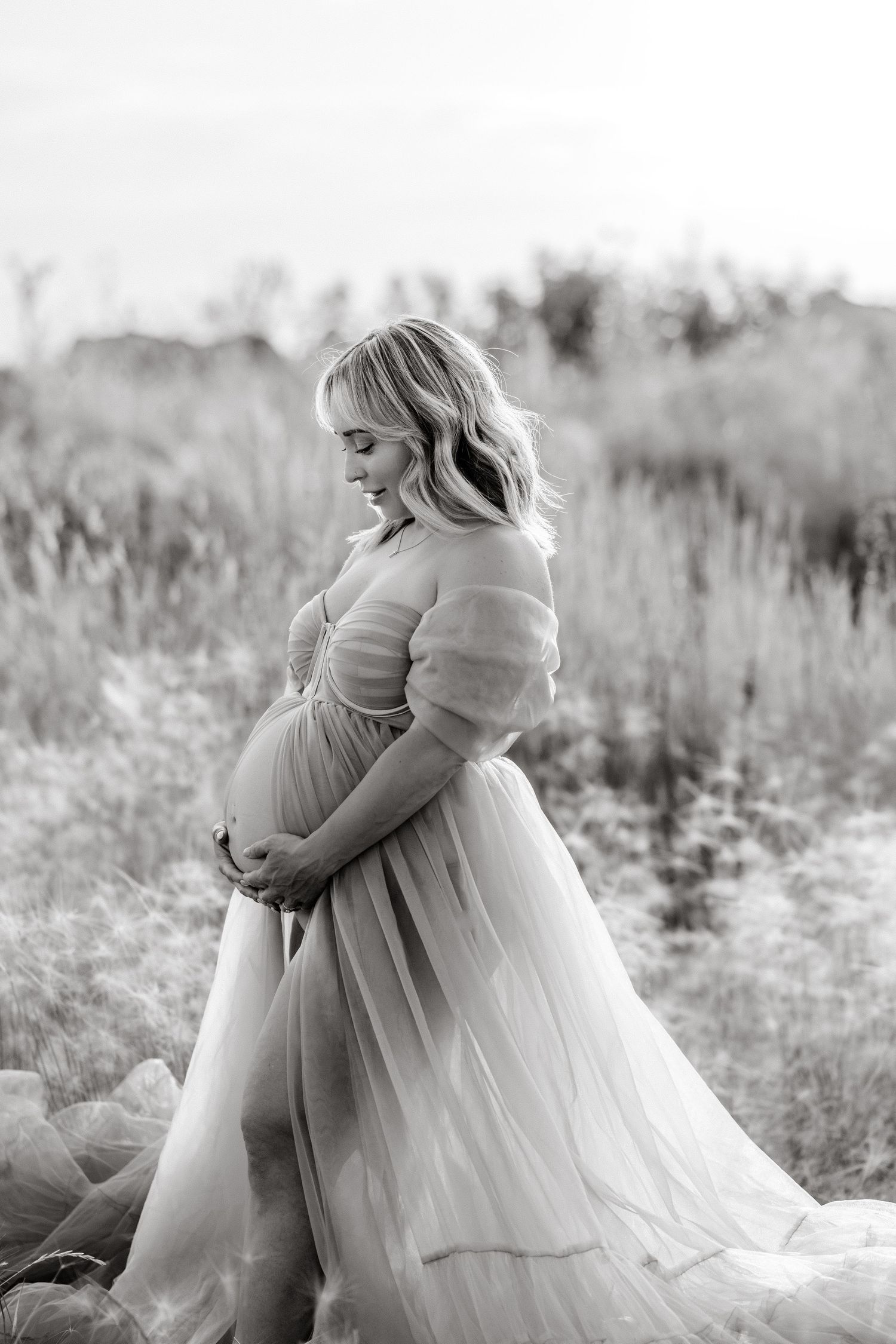 Black and white portraits showing tender moments between family members in a sunlit field.