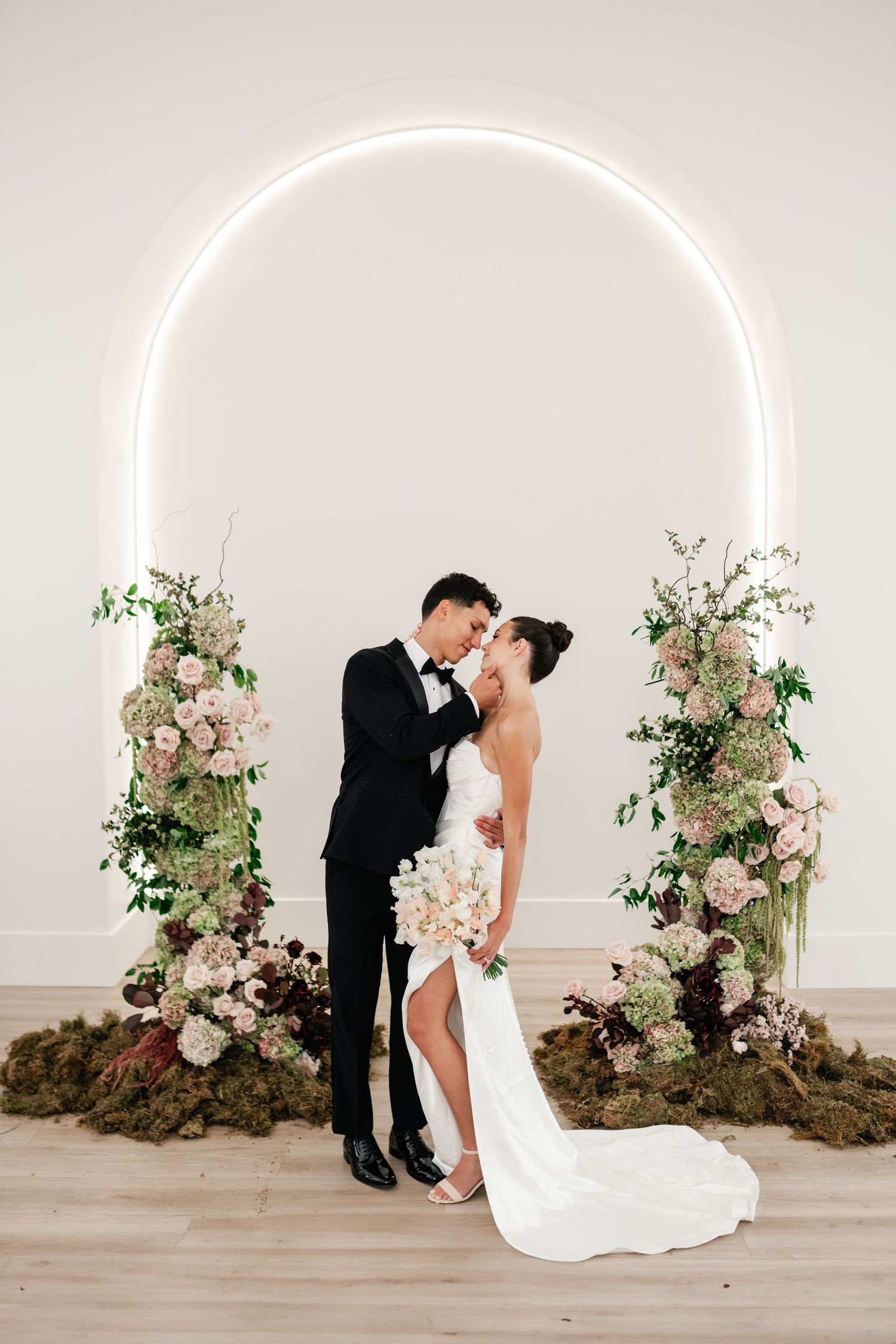 Elegant wedding photo with illuminated neon circle arch and romantic florals at Moments on Main, a Utah County wedding venue.