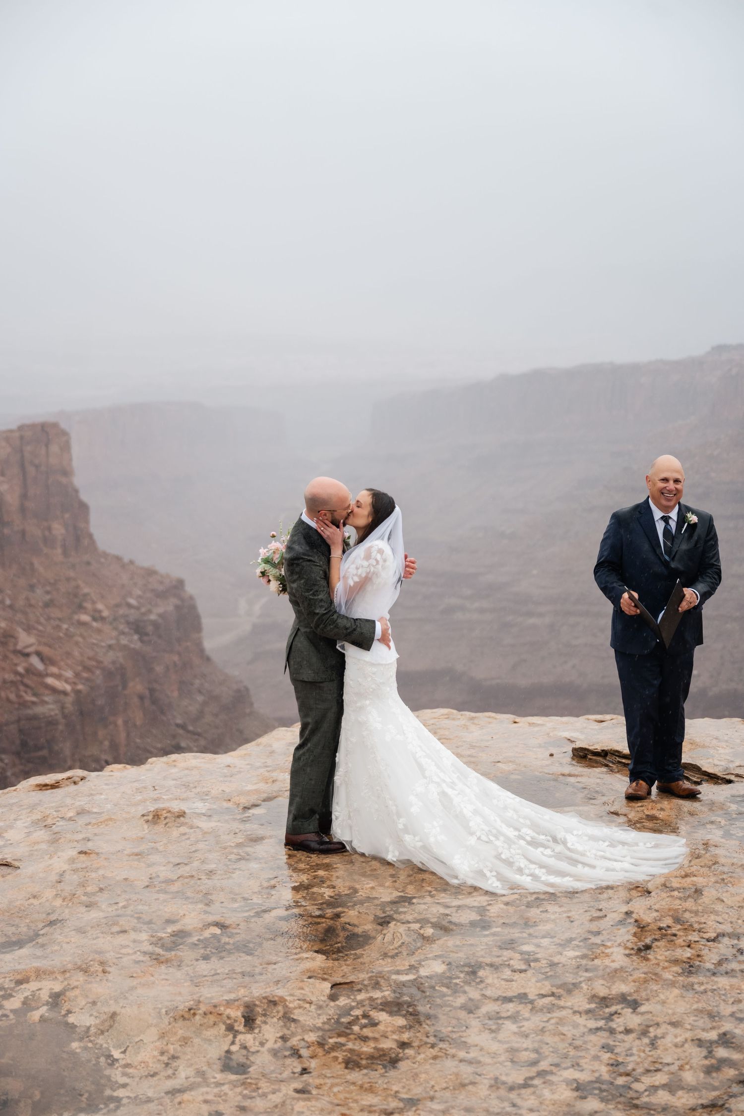 Emotional wedding ceremony moments captured on dramatic canyon overlook with misty backdrop.