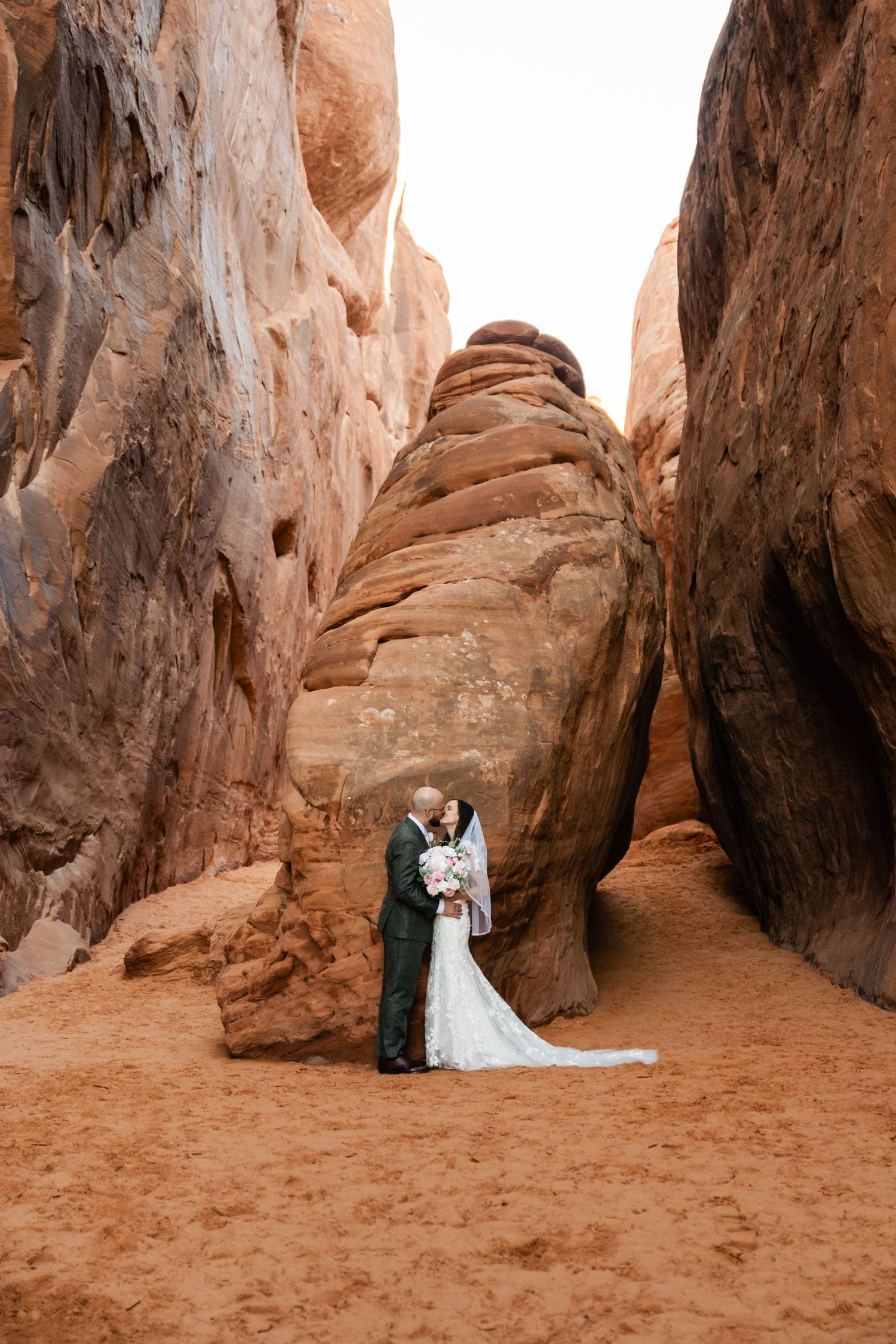 A wedding portrait captured in a dramatic red rock canyon with towering sandstone walls.