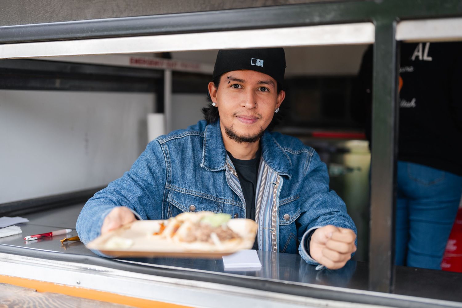 Food truck workers prepare and serve meals through service window.