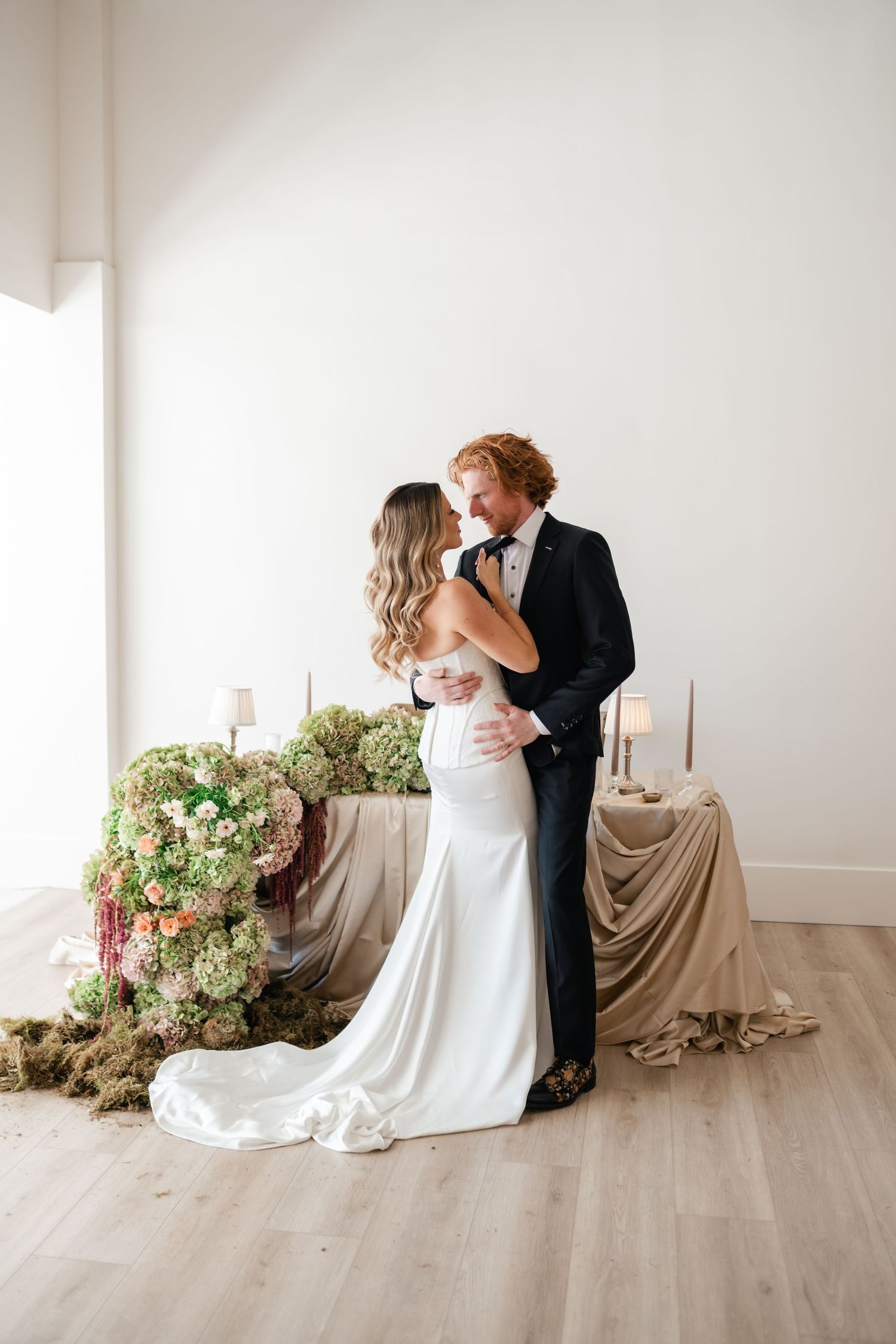 Couple in wedding attire sharing intimate moments at Moments on Main with floral arrangements. Utah Wedding Photographer.