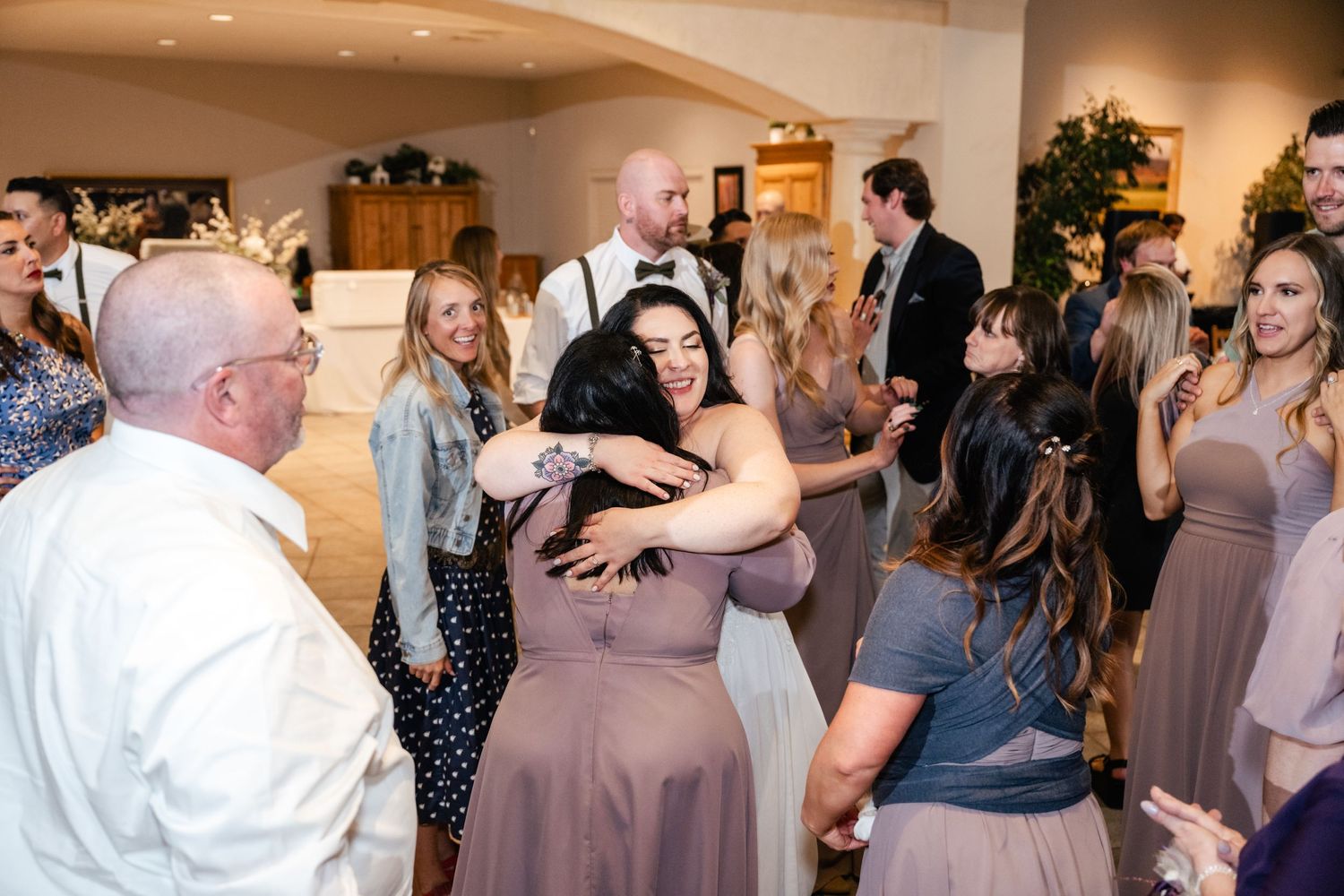 People dancing and enjoying themselves at a wedding reception in an indoor venue with soft lighting.
