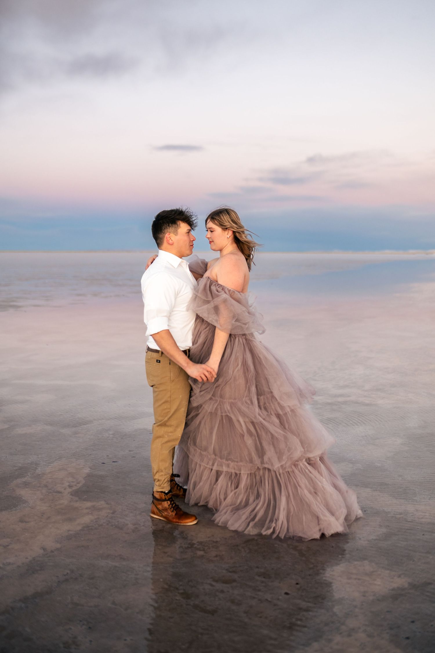 A couple holds hands as blue hour enhances the romance of a couple's photo session at the flooded Salt Flats.