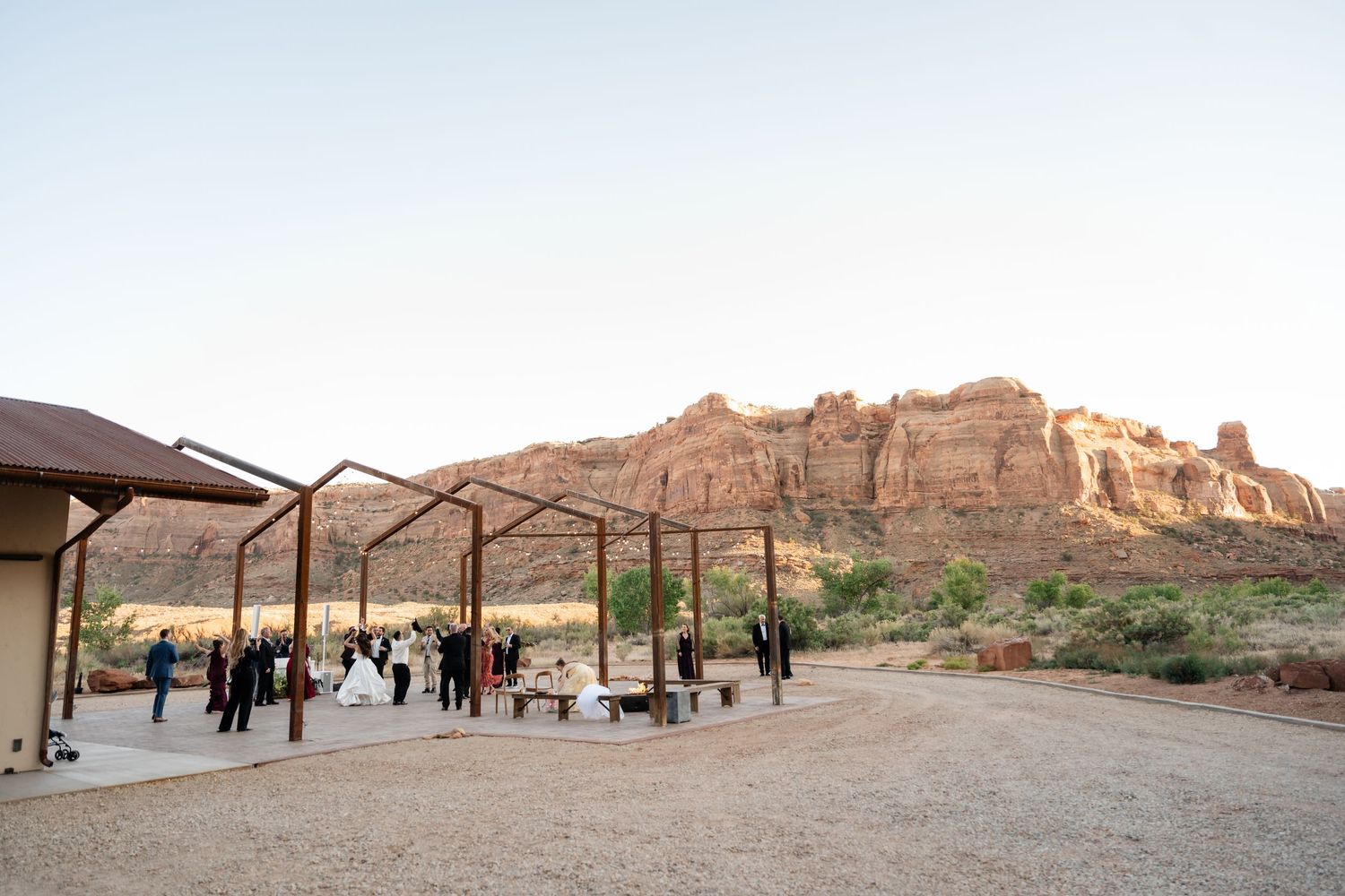 Outdoor wedding ceremony in Moab Utah with red rock canyon backdrop and rustic pergola structure at golden hour.