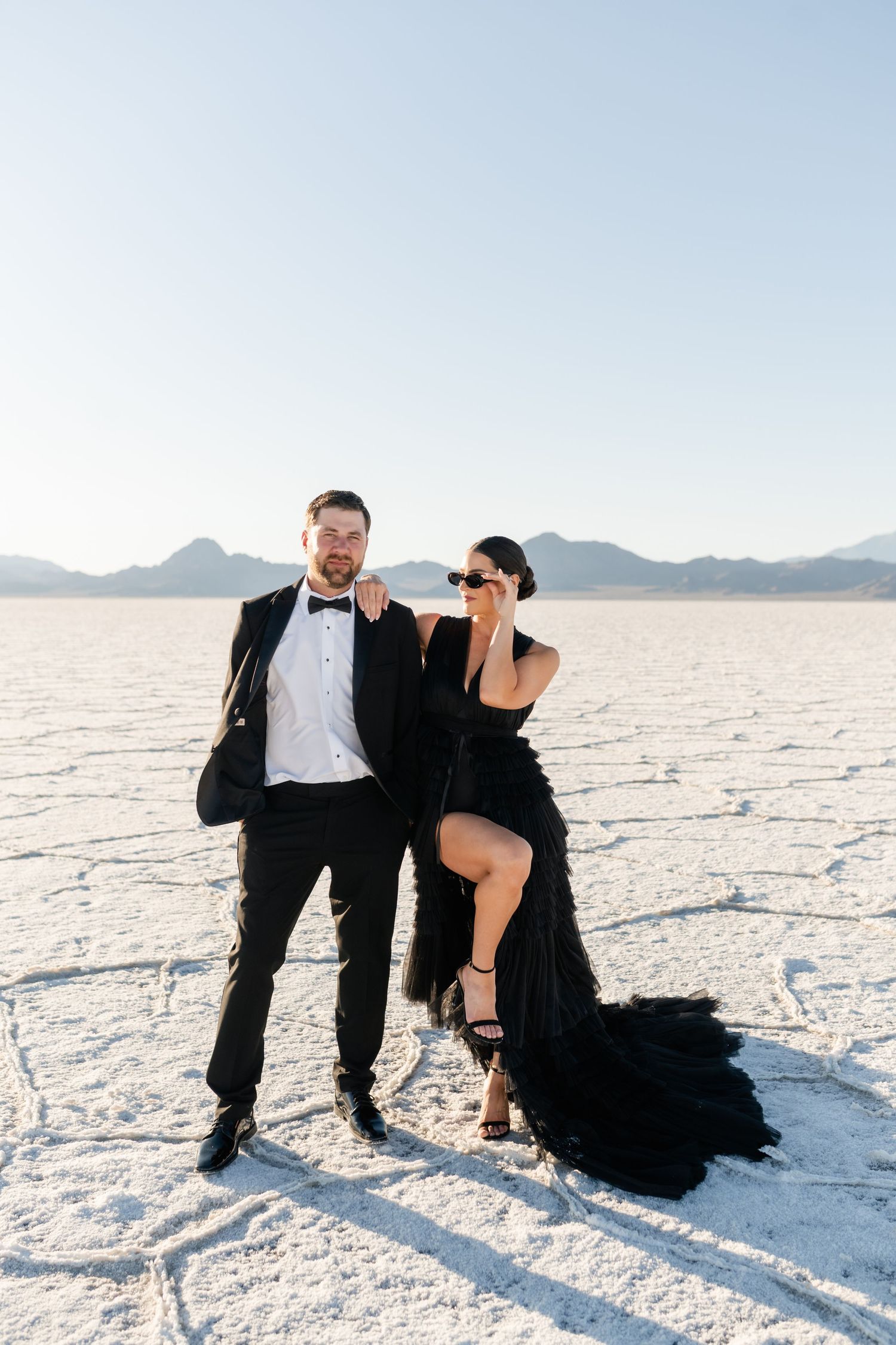 Salt Flats Photographer. A playful couple's photoshoot on salt flats with dramatic poses and formal attire.