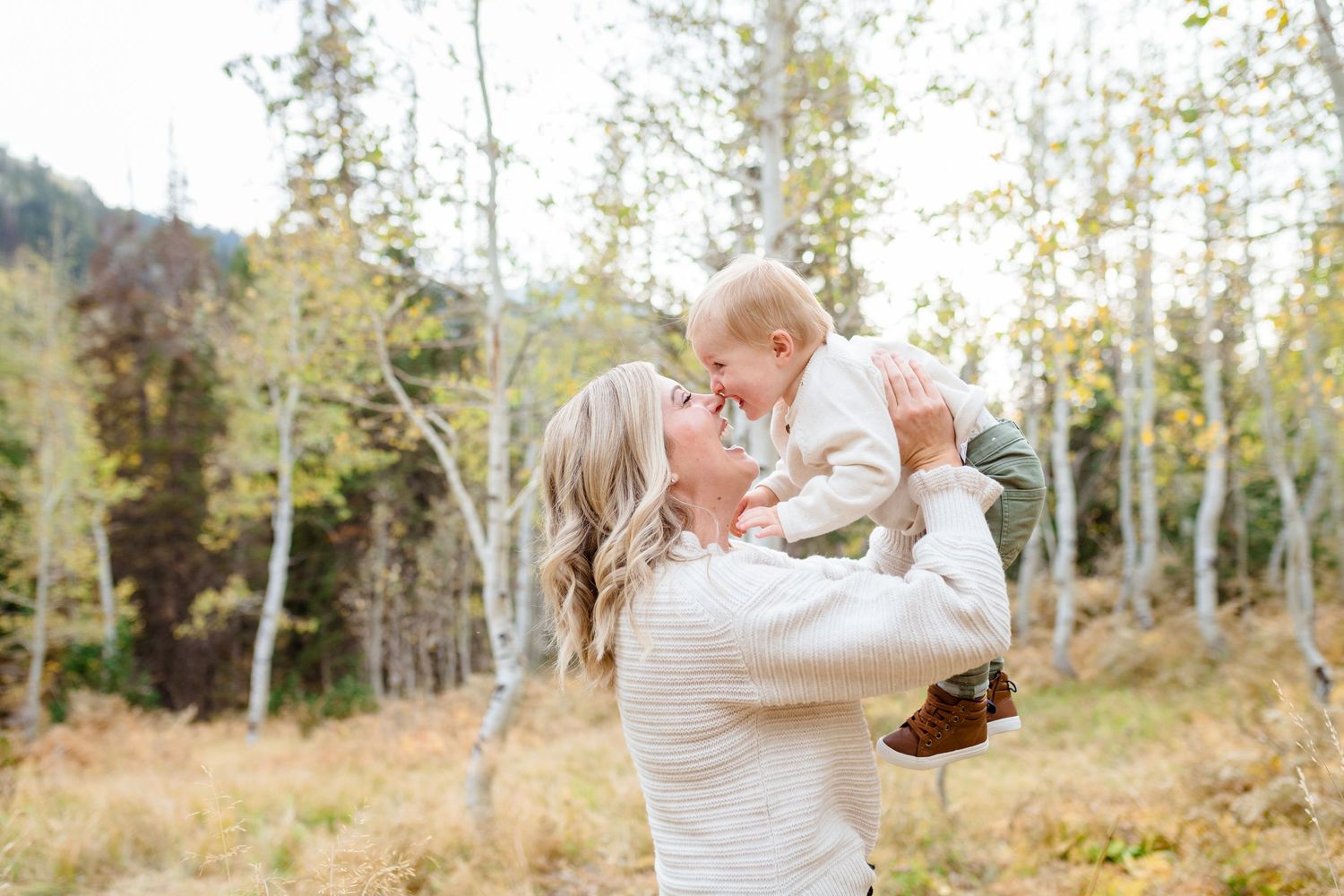 A couple in white embraces during a romantic outdoor photo session among aspen trees in autumn.