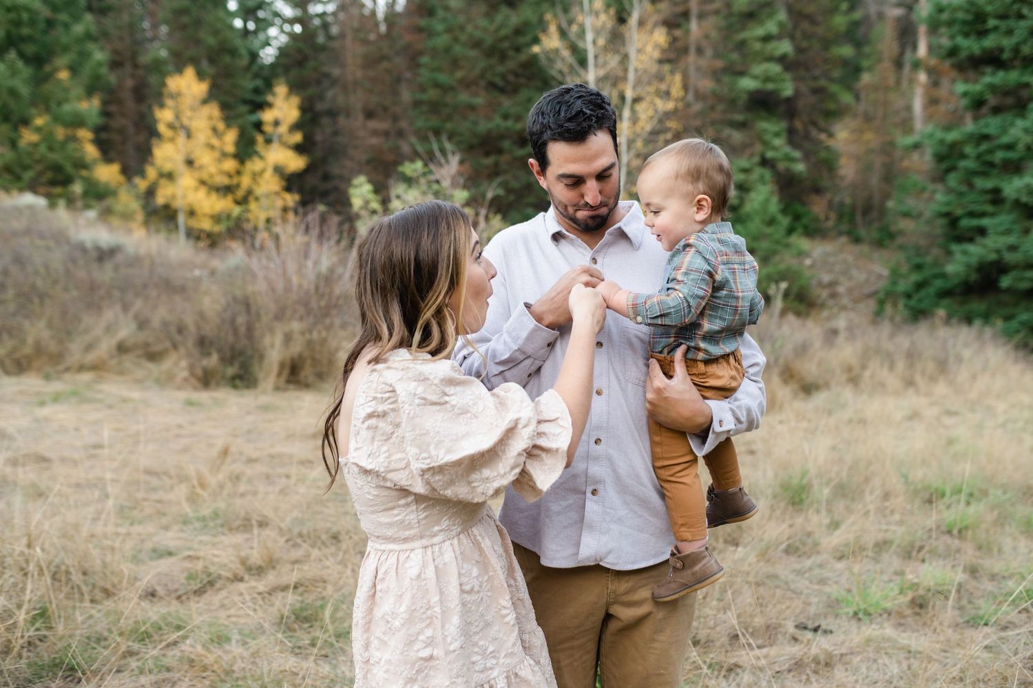 A family in coordinating outfits walks together through a scenic outdoor setting during an autumn photo session.