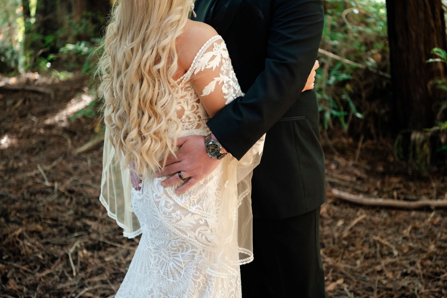 An intimate wedding moment captured among towering redwood trees in a serene forest setting.