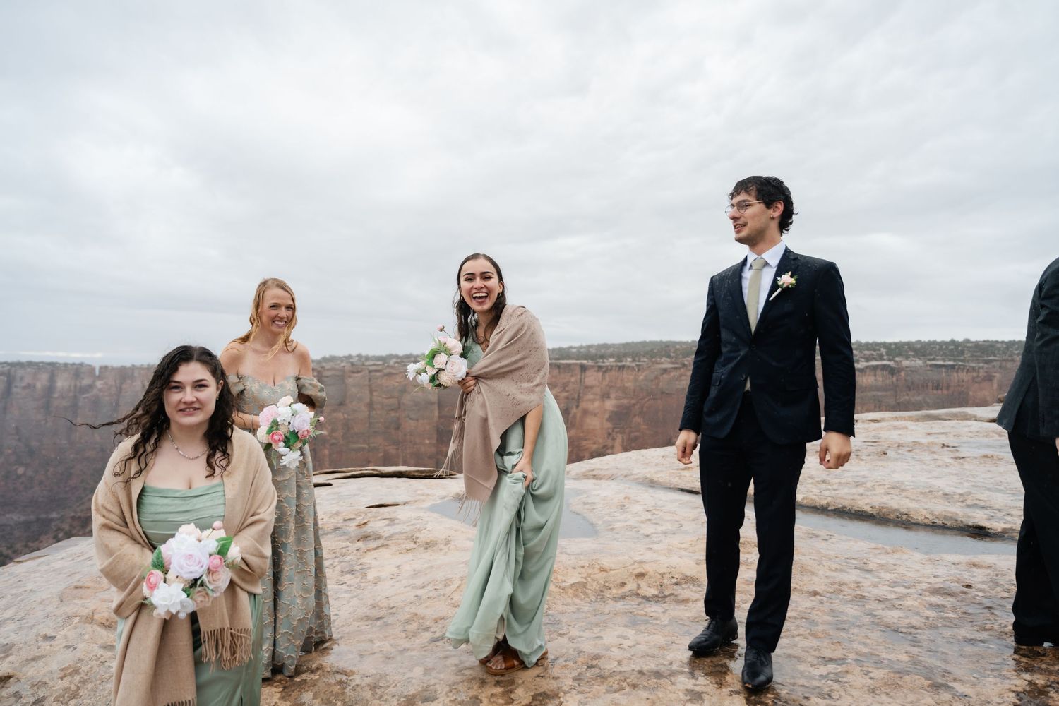 Wedding party walking along desert cliff edge with dramatic canyon views.
